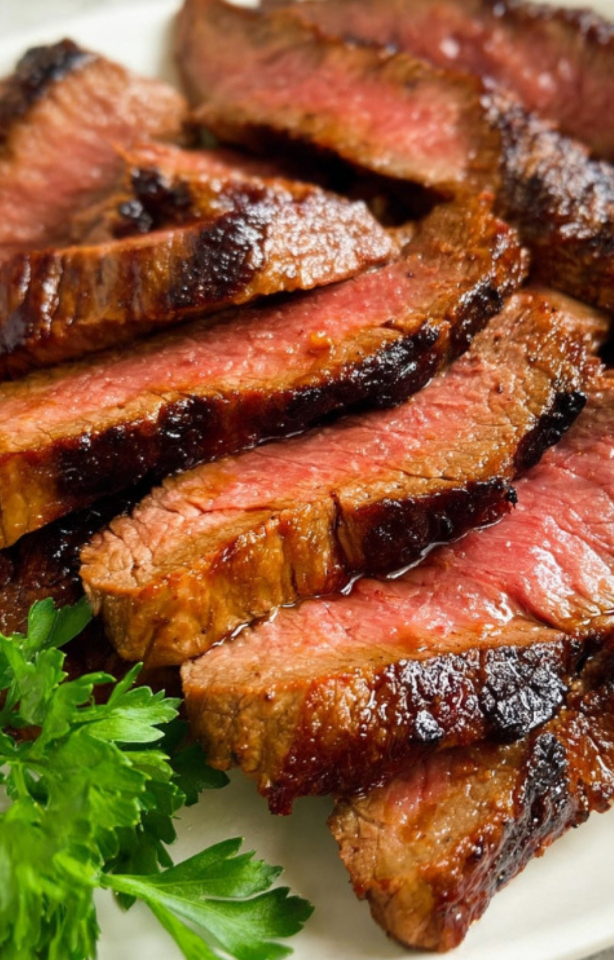 Medium-rare marinated flank steak sliced on a plate, juicy and tender, ideal for family dinners or backyard cookouts.