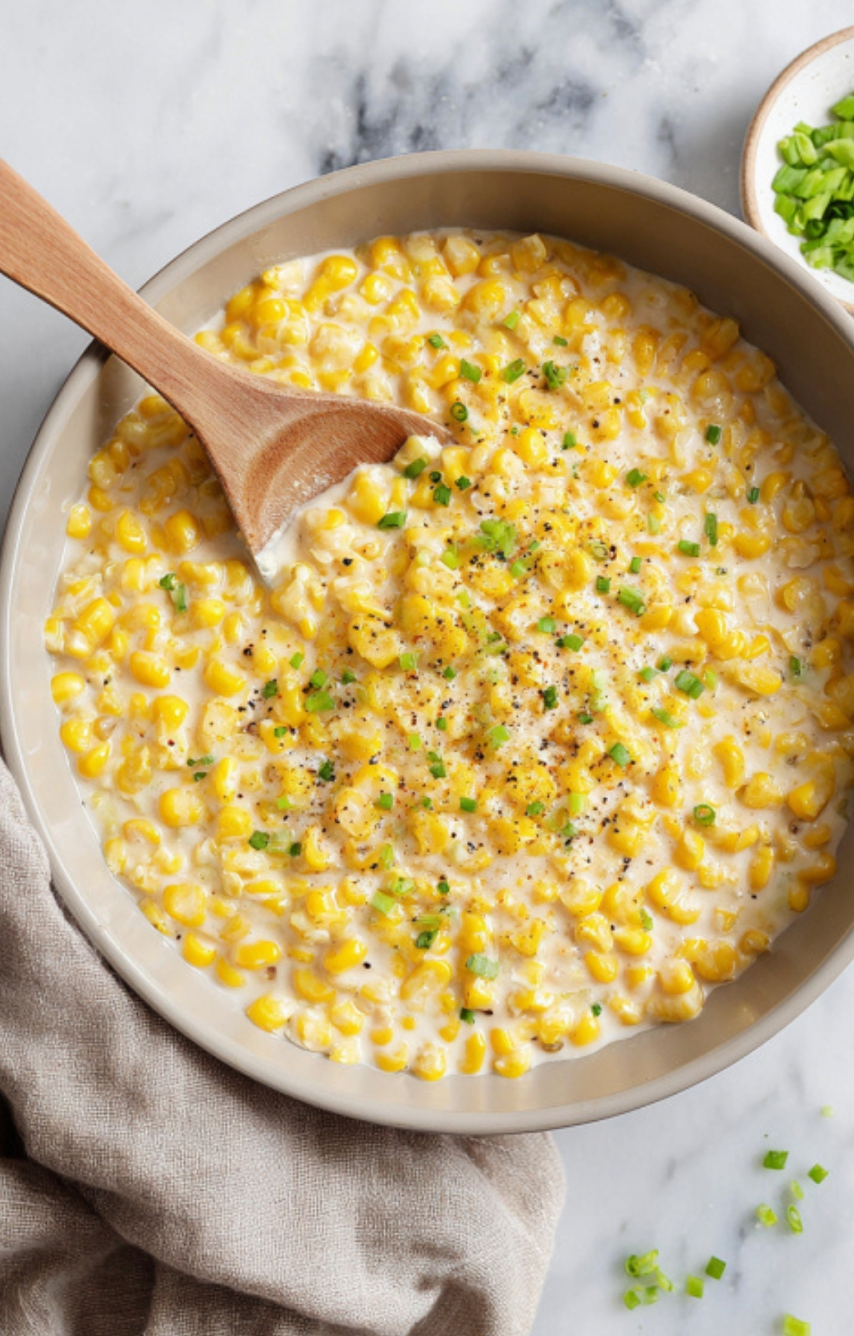 Freshly cooked creamy canned corn in a pan, garnished with green onions and black pepper. This Southern-inspired side is a staple for Thanksgiving or Christmas feasts.