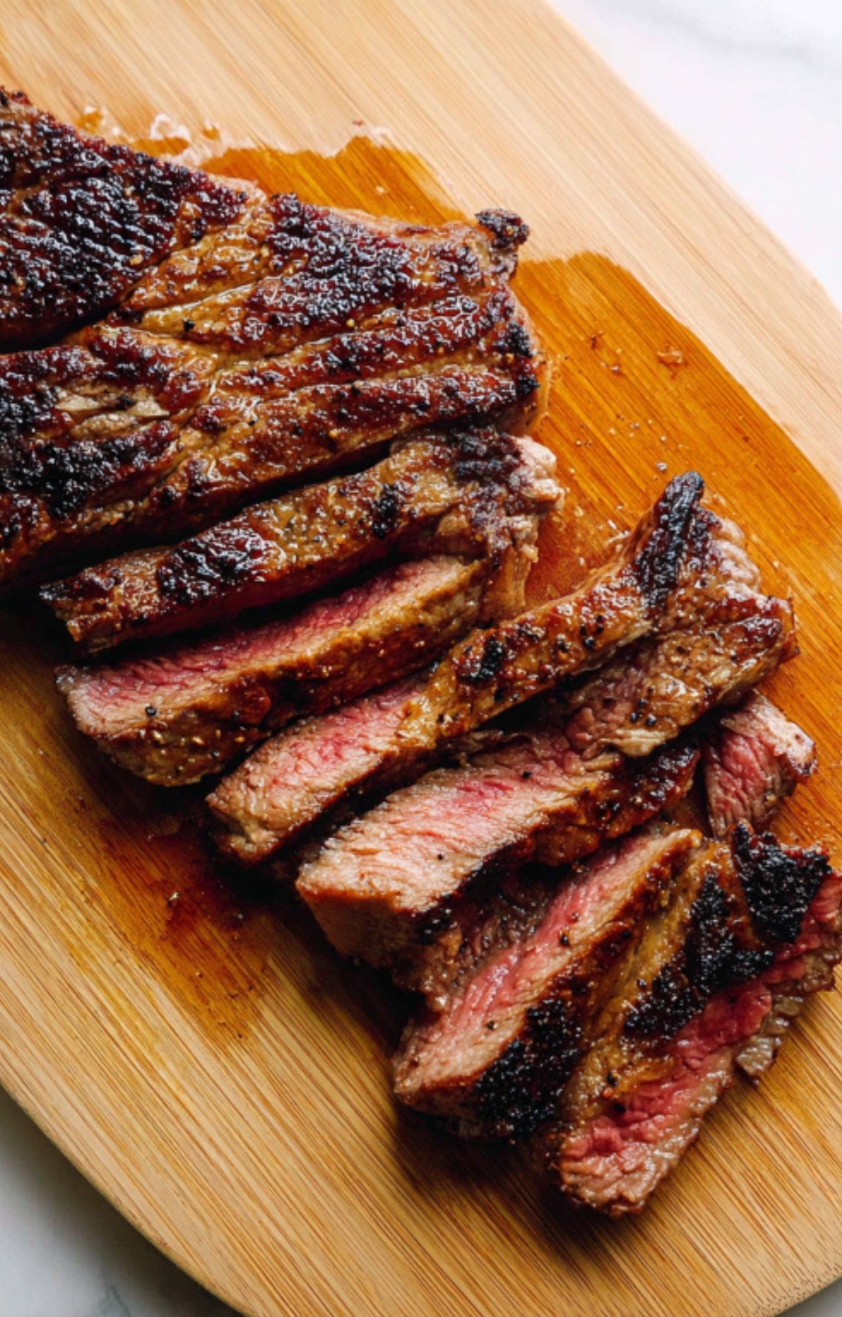Sliced steak on a wooden board, showing juicy pink center and seared crust for a weeknight meal.