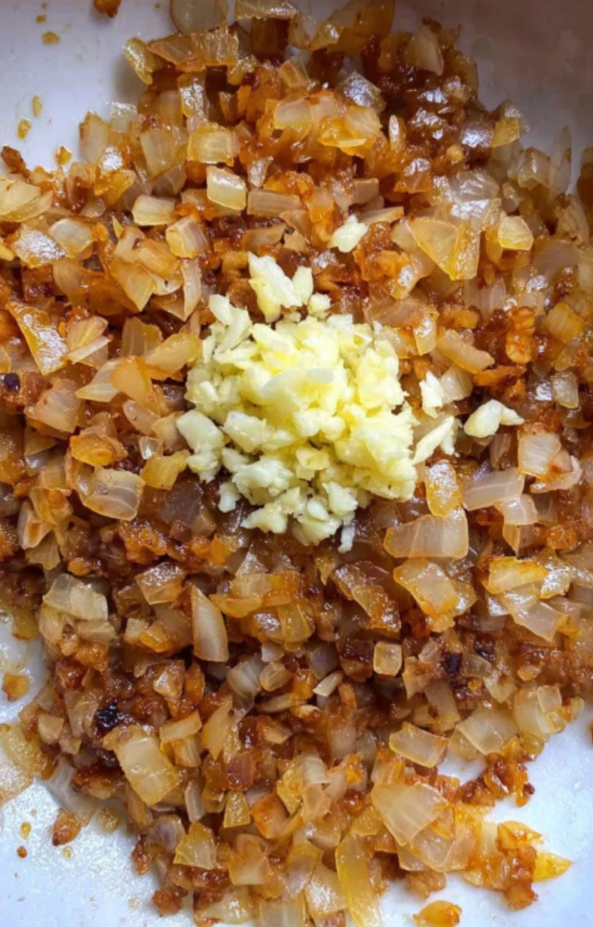 A pan filled with caramelized onions and fresh minced garlic, the secret to rich, authentic German goulash flavor. Simple step for every home cook.