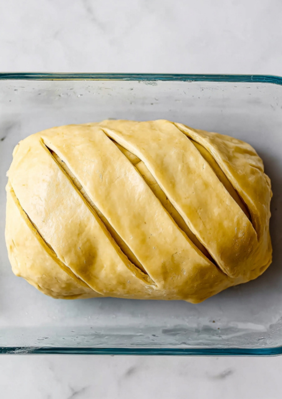 Unbaked beef wellington wrapped in puff pastry with slits on top, ready to bake as a festive holiday main dish or special dinner.