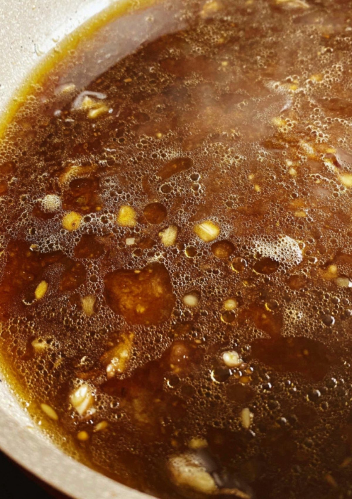 Soy citrus garlic sauce bubbling in a skillet for Beef Steak Filipino.