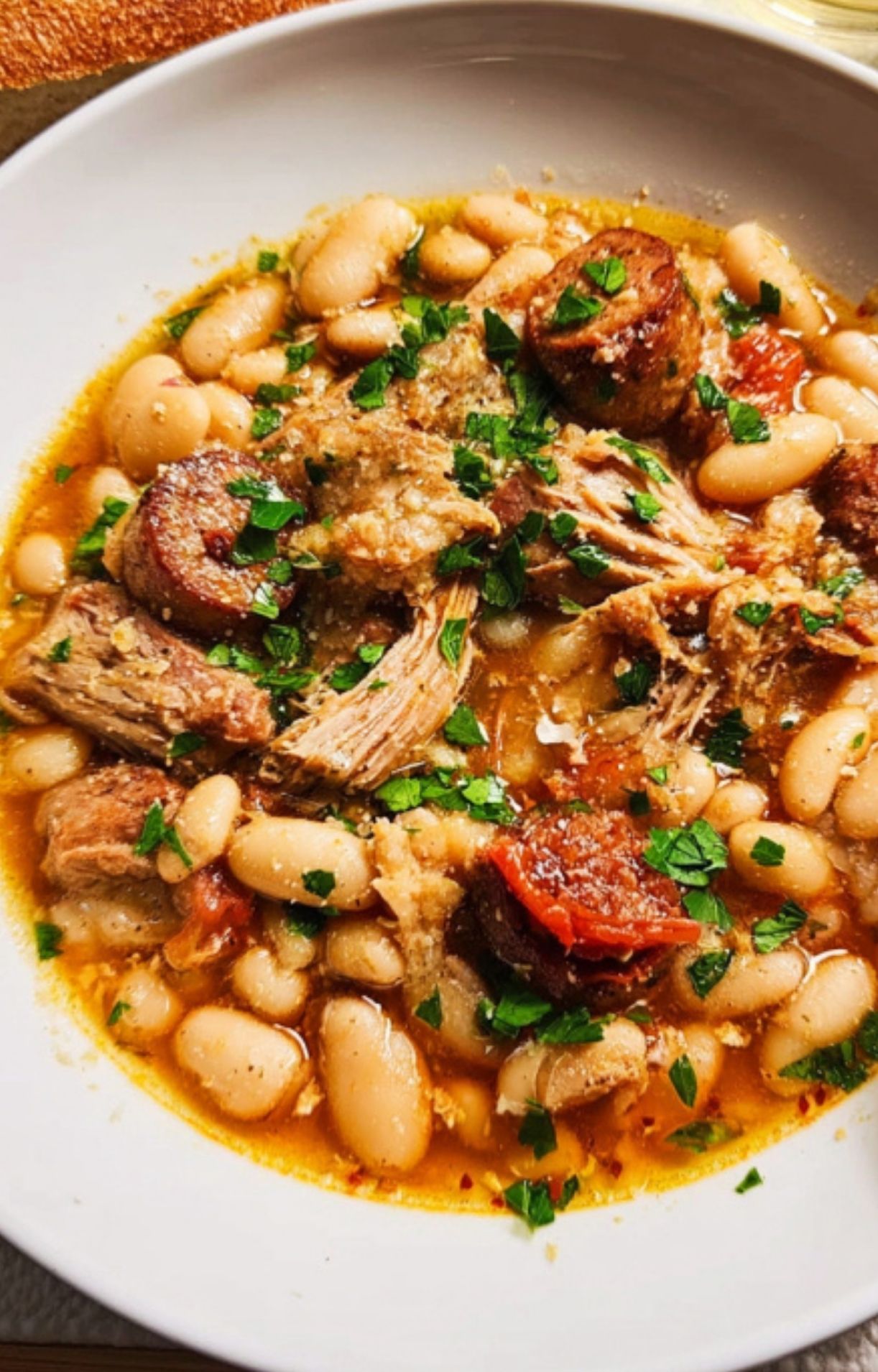 Close-up of a bowl of cassolette showing beans, sausage, and pork, a rustic French casserole dish that’s perfect for comforting winter dinners and special occasions.