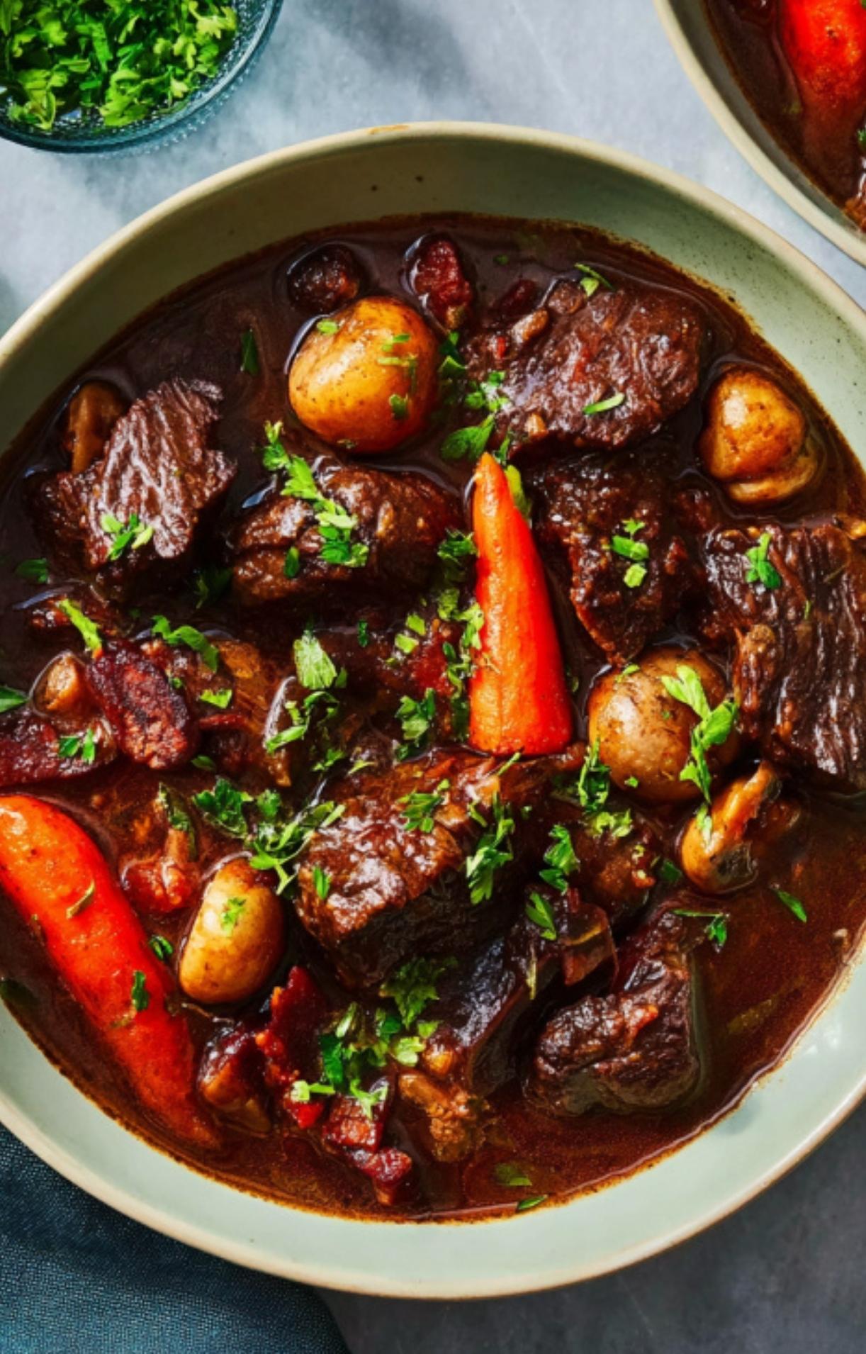 A bowl of classic French beef stew with tender beef, baby carrots, pearl onions, mushrooms, and fresh parsley. A comforting winter recipe perfect for Sunday dinners and holiday gatherings.