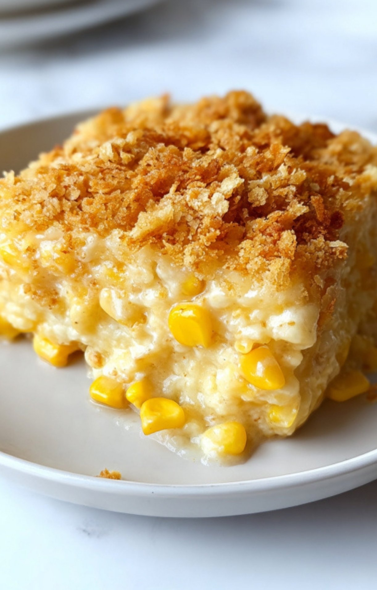 Plate with a thick slice of scalloped corn casserole showing sweet corn and rich, golden crust, a comforting Southern side.