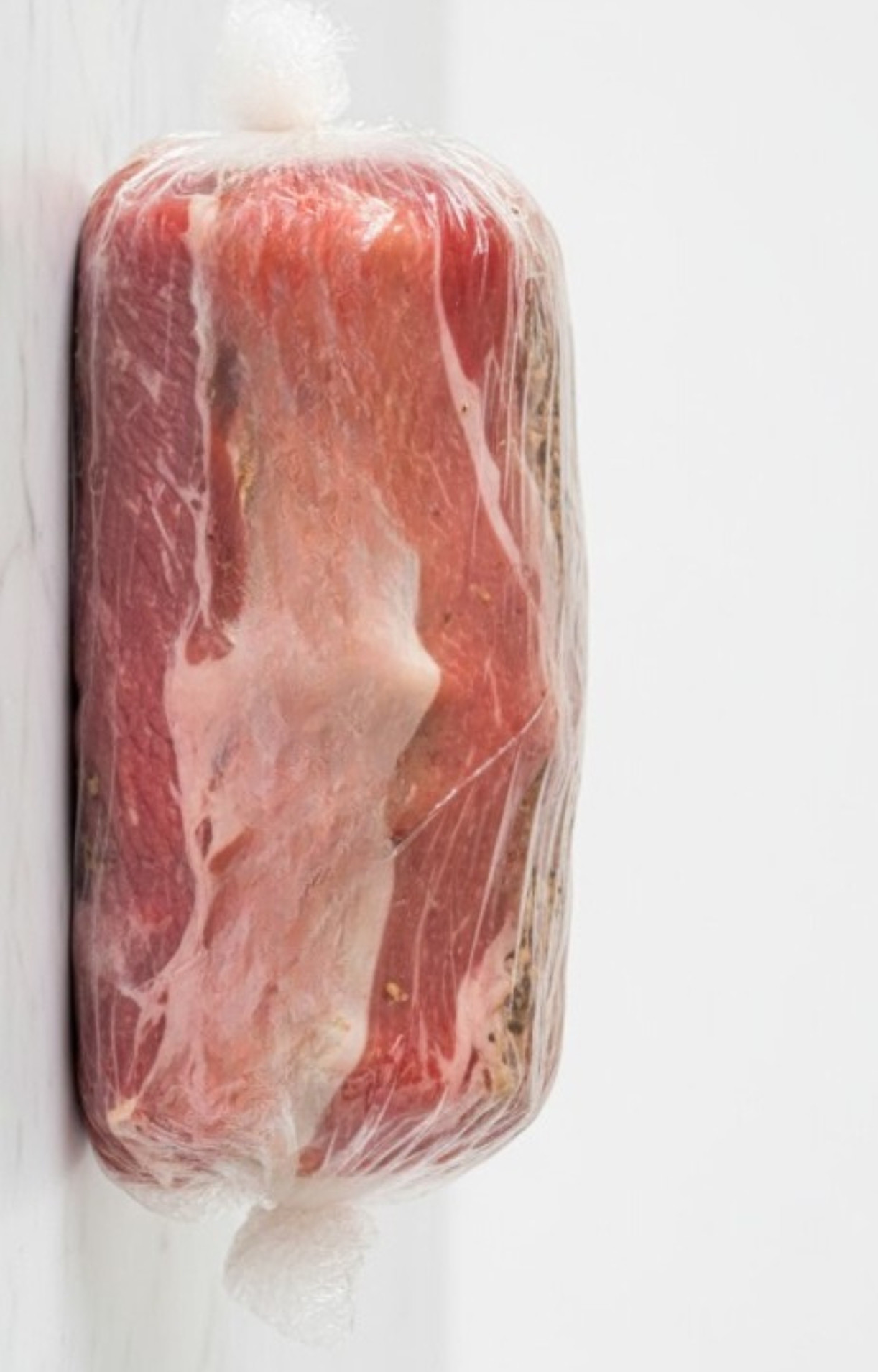 Beef wellington wrapped tightly in plastic wrap to chill and set the shape before baking, a key step for perfect results with beef tenderloin.