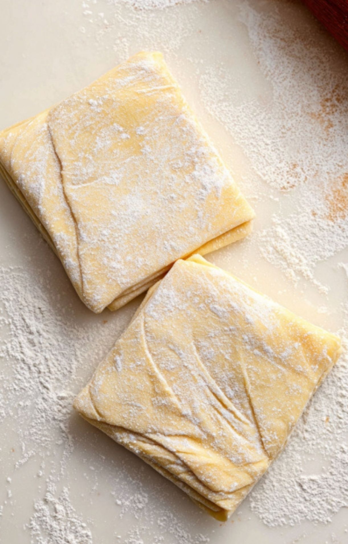 Neatly folded puff pastry squares on a floured surface, the key step for wrapping individual filet mignon beef Wellington.