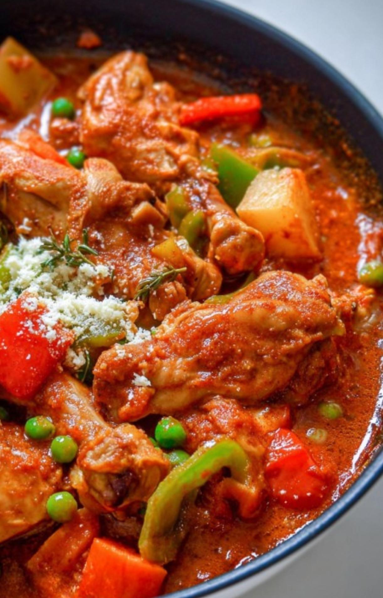 Chicken caldereta with carrots, potatoes, bell peppers, green peas, and a rich tomato sauce. Topped with grated cheese and fresh herbs. Hearty Filipino dish for family meals or special occasions.