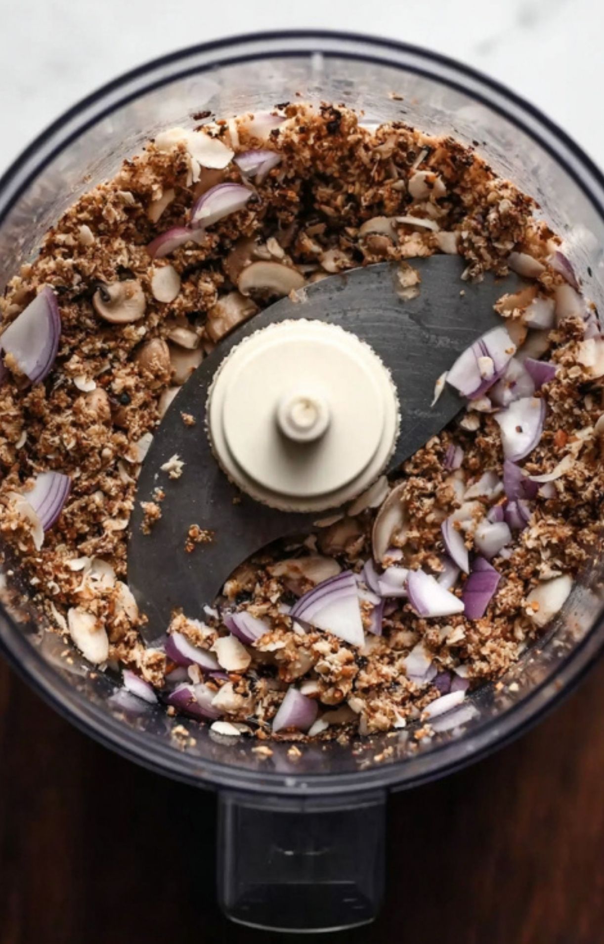 Mushrooms and shallots being finely chopped in a food processor, the first step in making flavorful duxelles for beef Wellington.