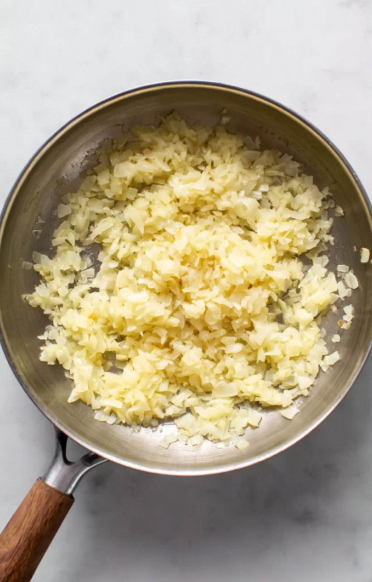 Chopped onions gently sautéed in a skillet until soft and golden. This step is part of the classic beef wellington recipe, adding rich flavor to the festive holiday dish.