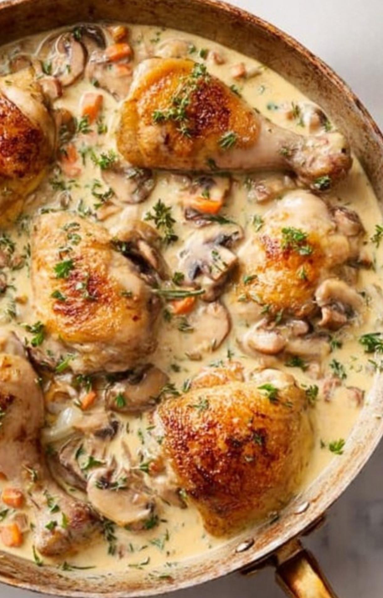 Chicken thighs and drumsticks in a skillet with creamy sauce, mushrooms, and herbs.