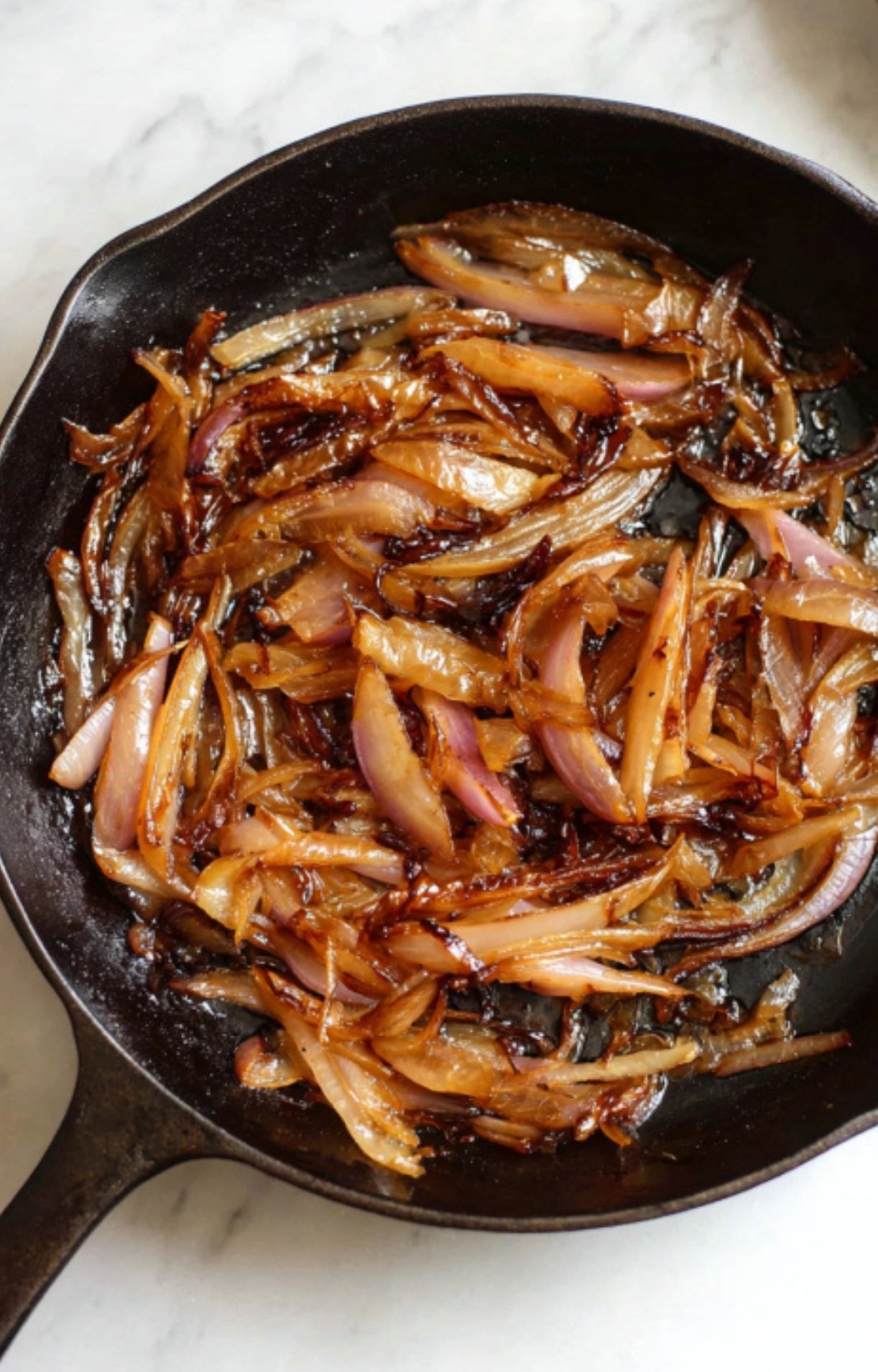 Golden brown, caramelized shallots in a cast iron pan, ready to top steak strips.