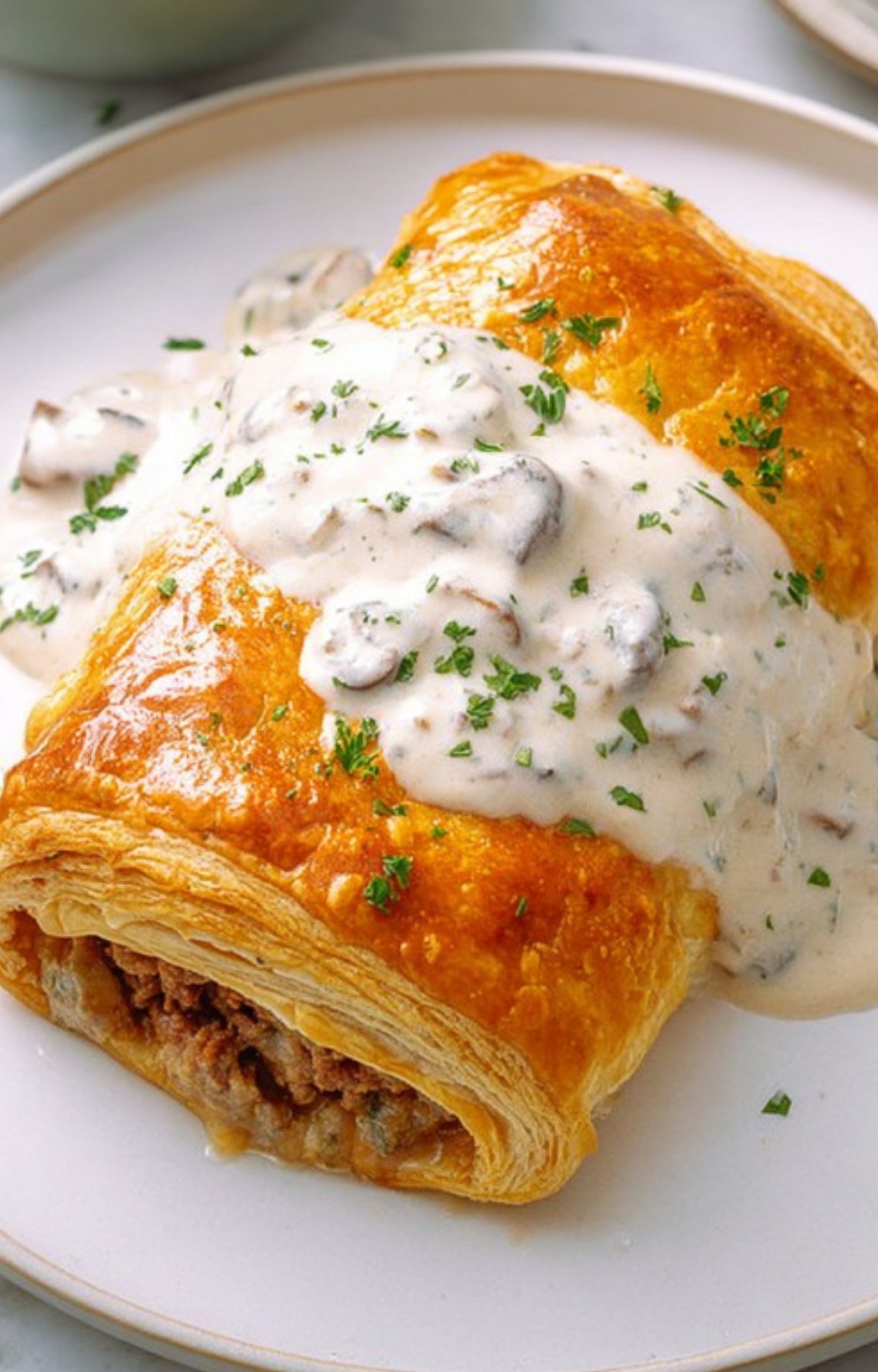 Golden Ground Beef Wellington topped with homemade creamy mushroom sauce, perfect for cozy dinners and holiday meals.