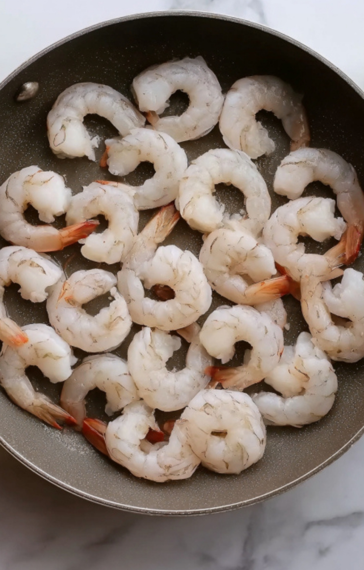 Raw shrimp cooking in a skillet – perfect protein option for fast, healthy dinners