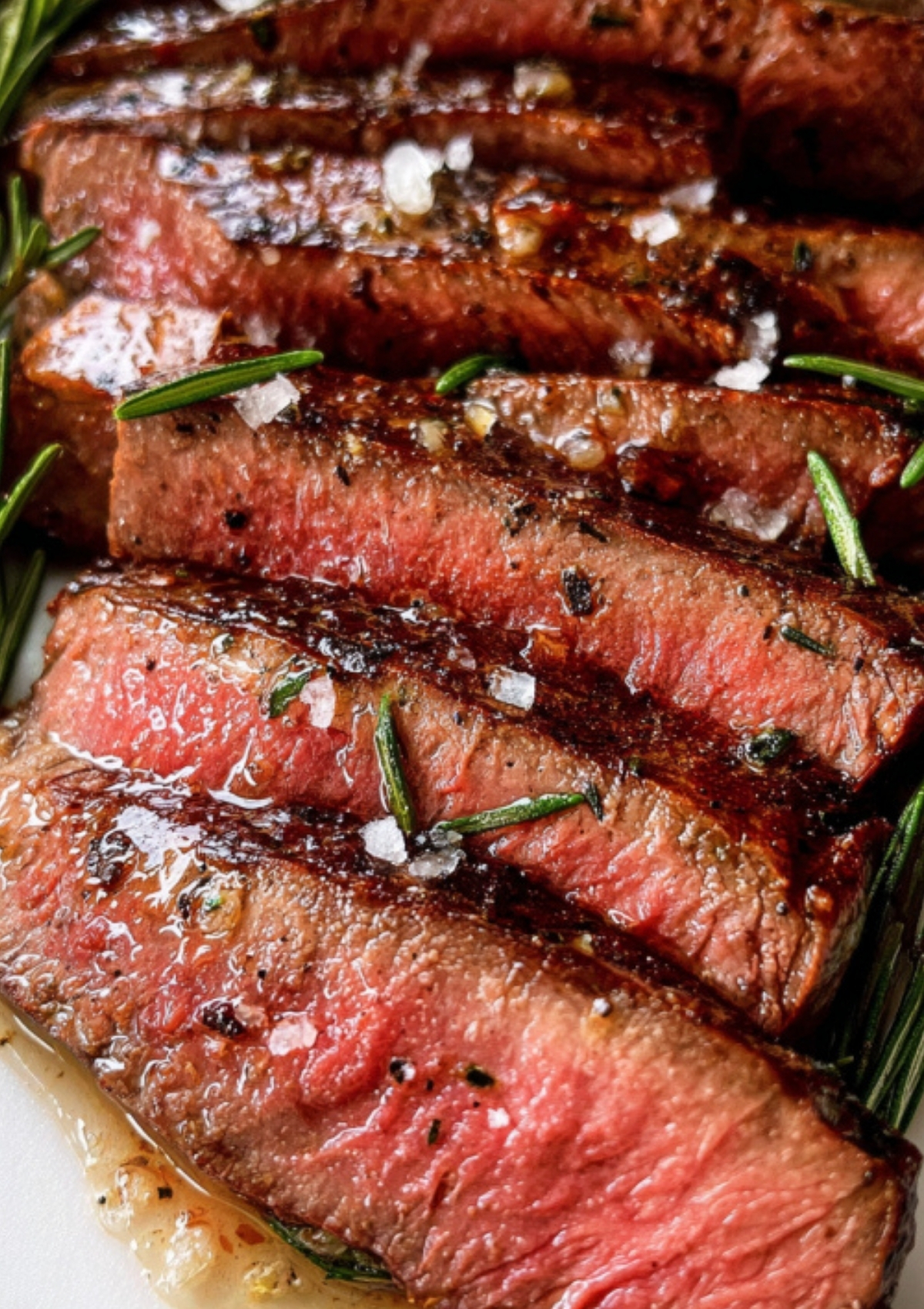 Close up of sliced round steak with rosemary and flaky salt, showcasing a juicy round steak recipe perfect for easy dinner nights and beef lovers.