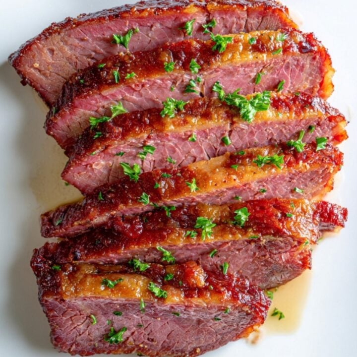 Overhead photo of oven baked corned beef, sliced and topped with fresh parsley. This holiday dinner classic is simple to make and full of savory flavor.