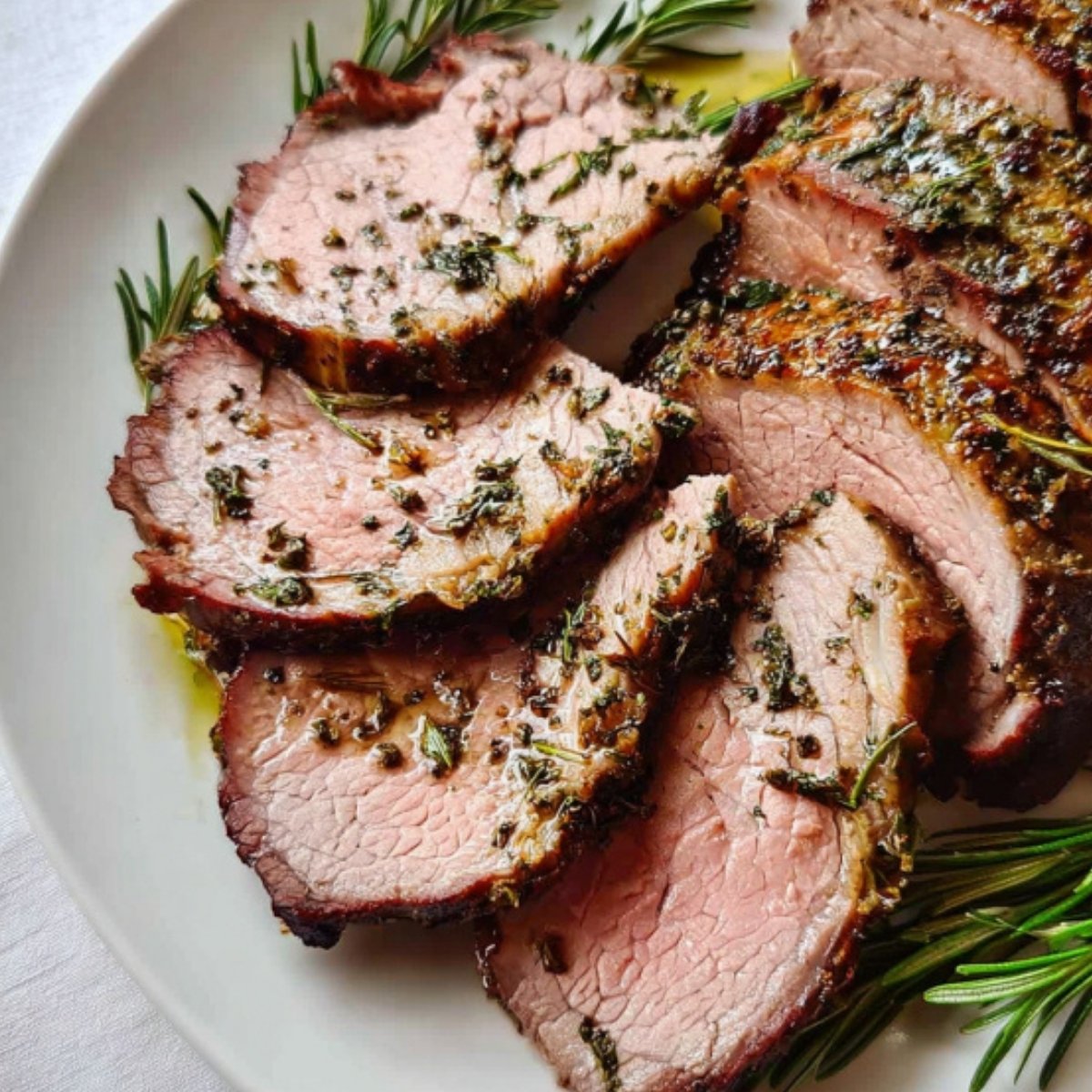 Sliced roast leg of lamb garnished with fresh rosemary