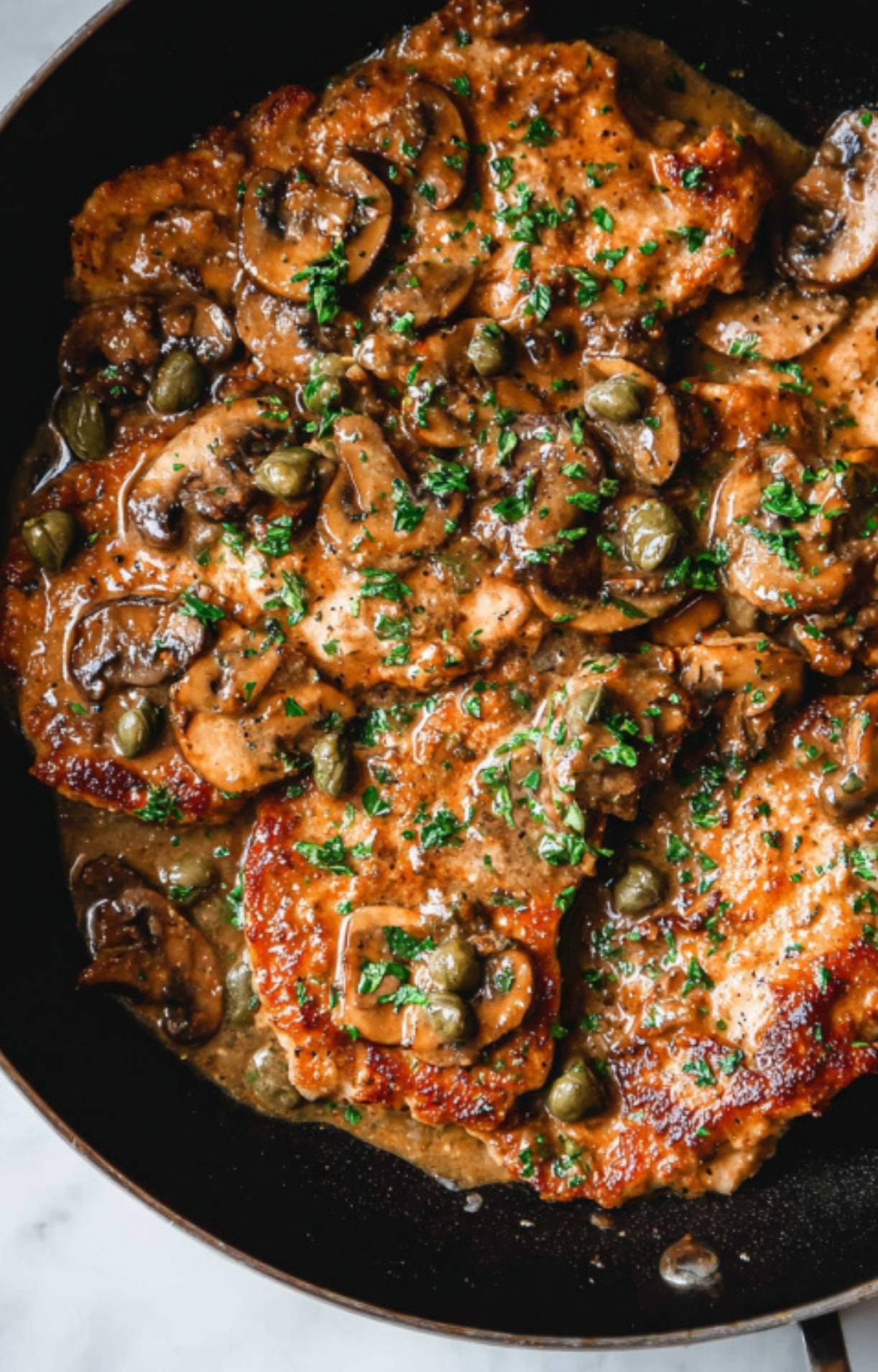 Golden veal scallopini simmering in a skillet with mushroom white wine sauce, capers, and fresh parsley. Easy Italian dinner perfect for weeknights or entertaining.