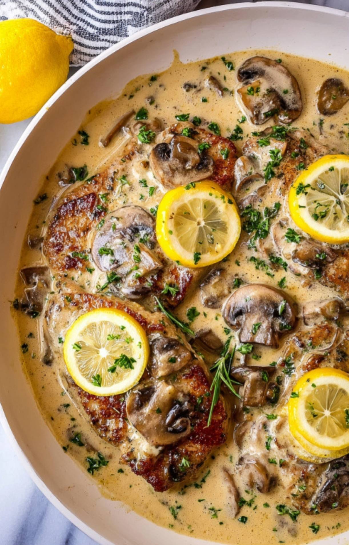 Sliced mushrooms simmering in a creamy white wine and rosemary sauce for authentic Italian veal scallopini.