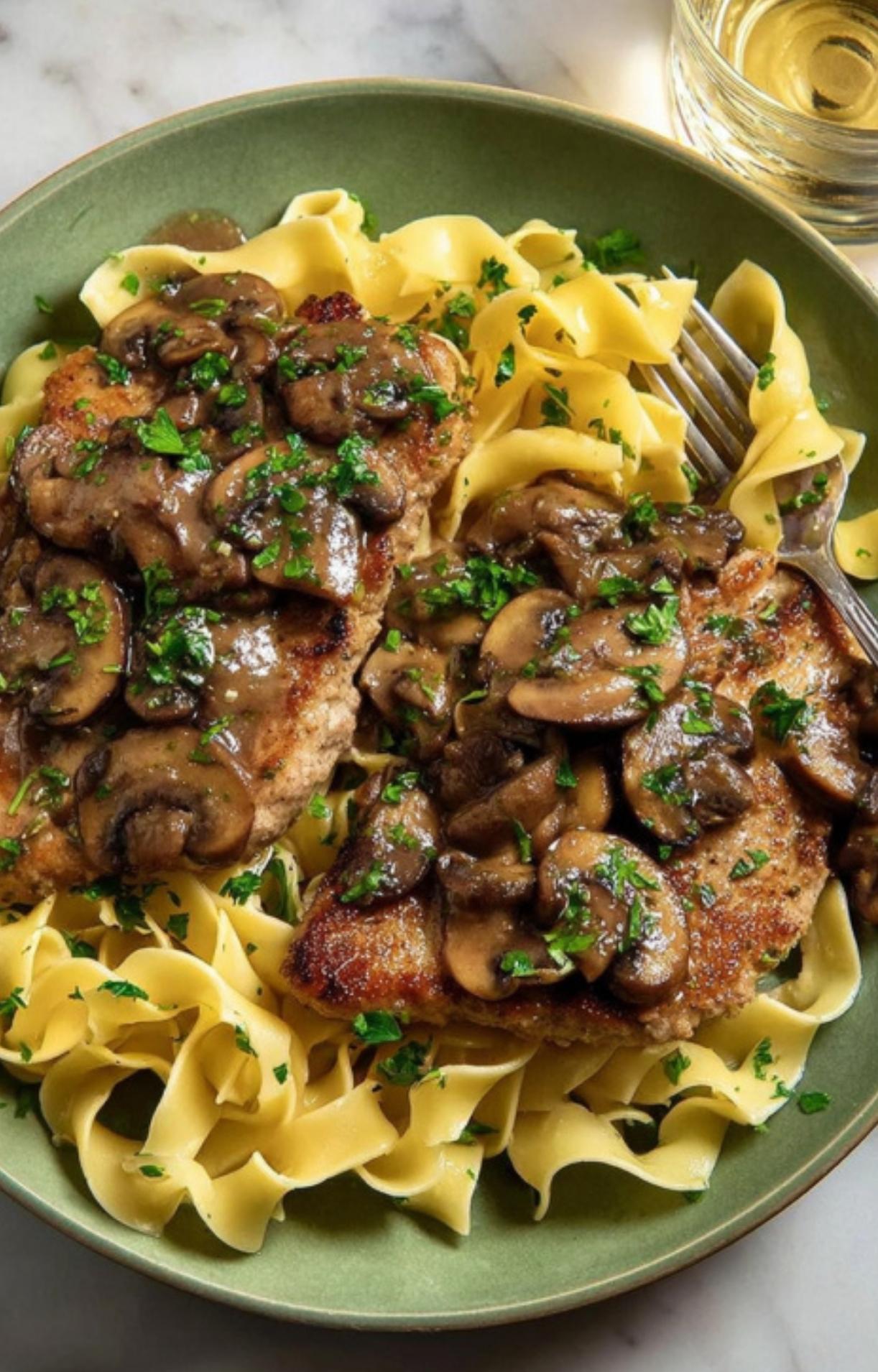Bowl of veal scallopini with mushroom sauce and egg noodles, garnished with parsley for a classic Italian comfort dinner.