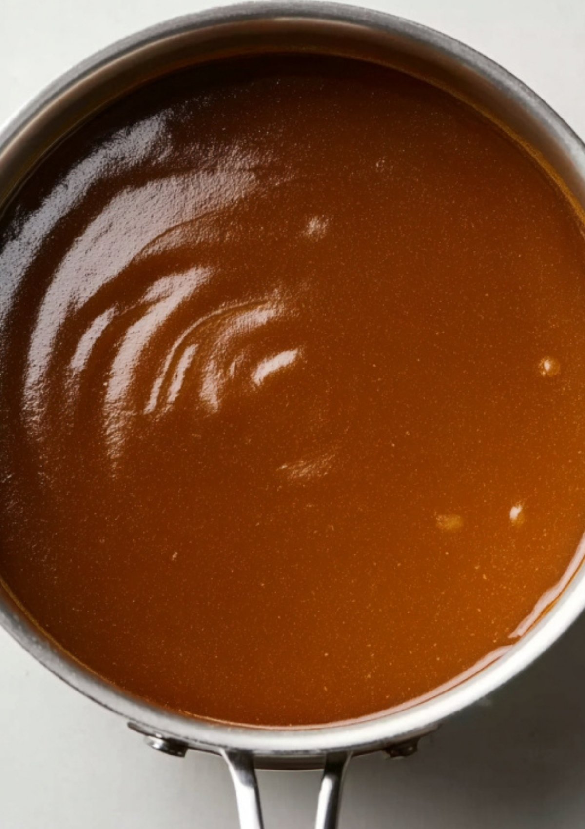 Smooth brown lamb gravy simmering in a saucepan