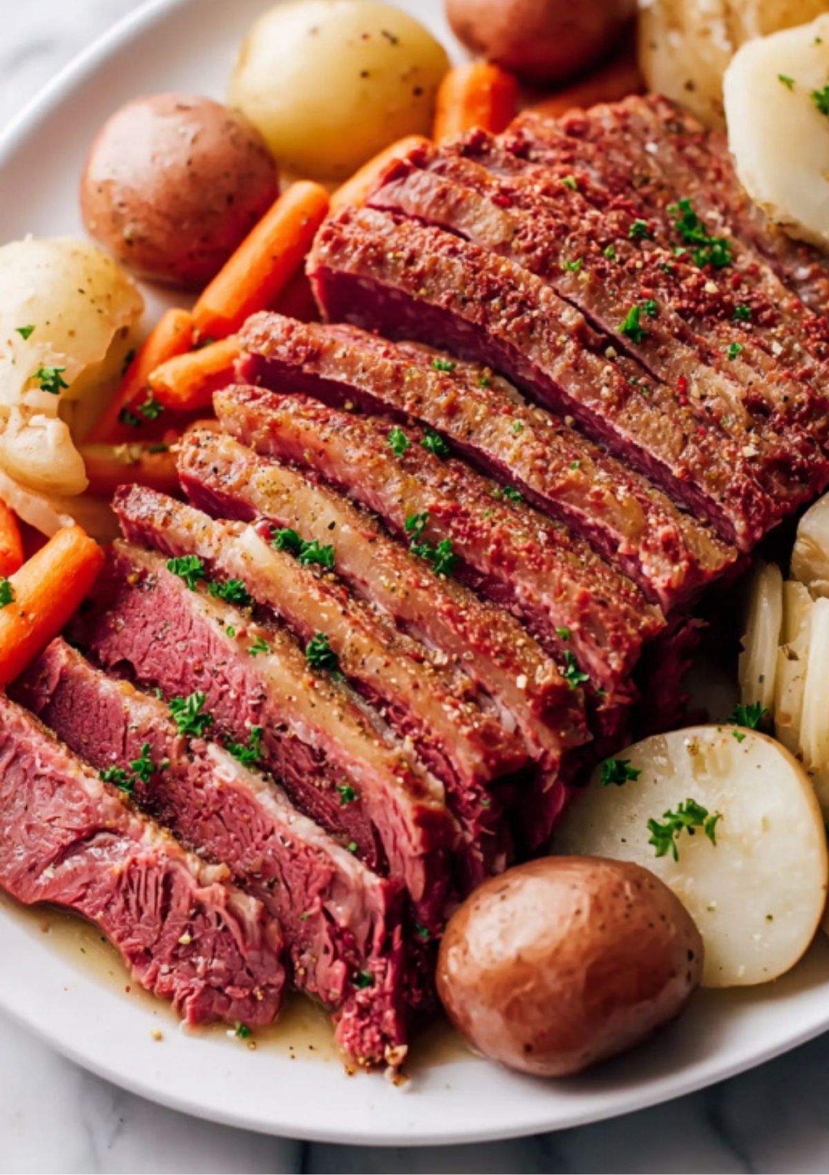 Thick, juicy slices of Instant Pot Corned Beef showing a tender texture, served alongside steamed carrots and potatoes.