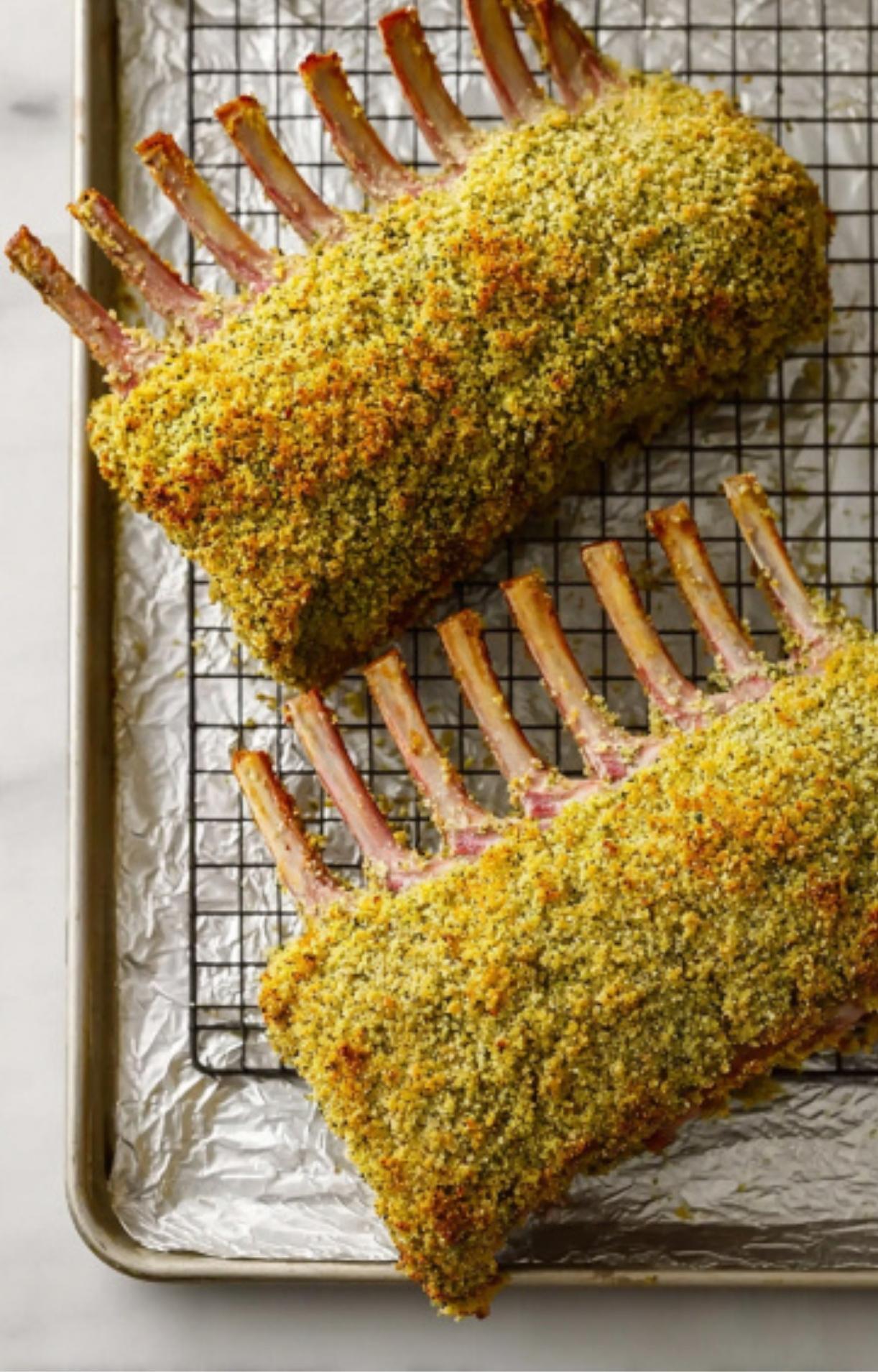 Two baked racks of lamb with crispy herb breadcrumb crust on a wire rack, ready to slice and serve