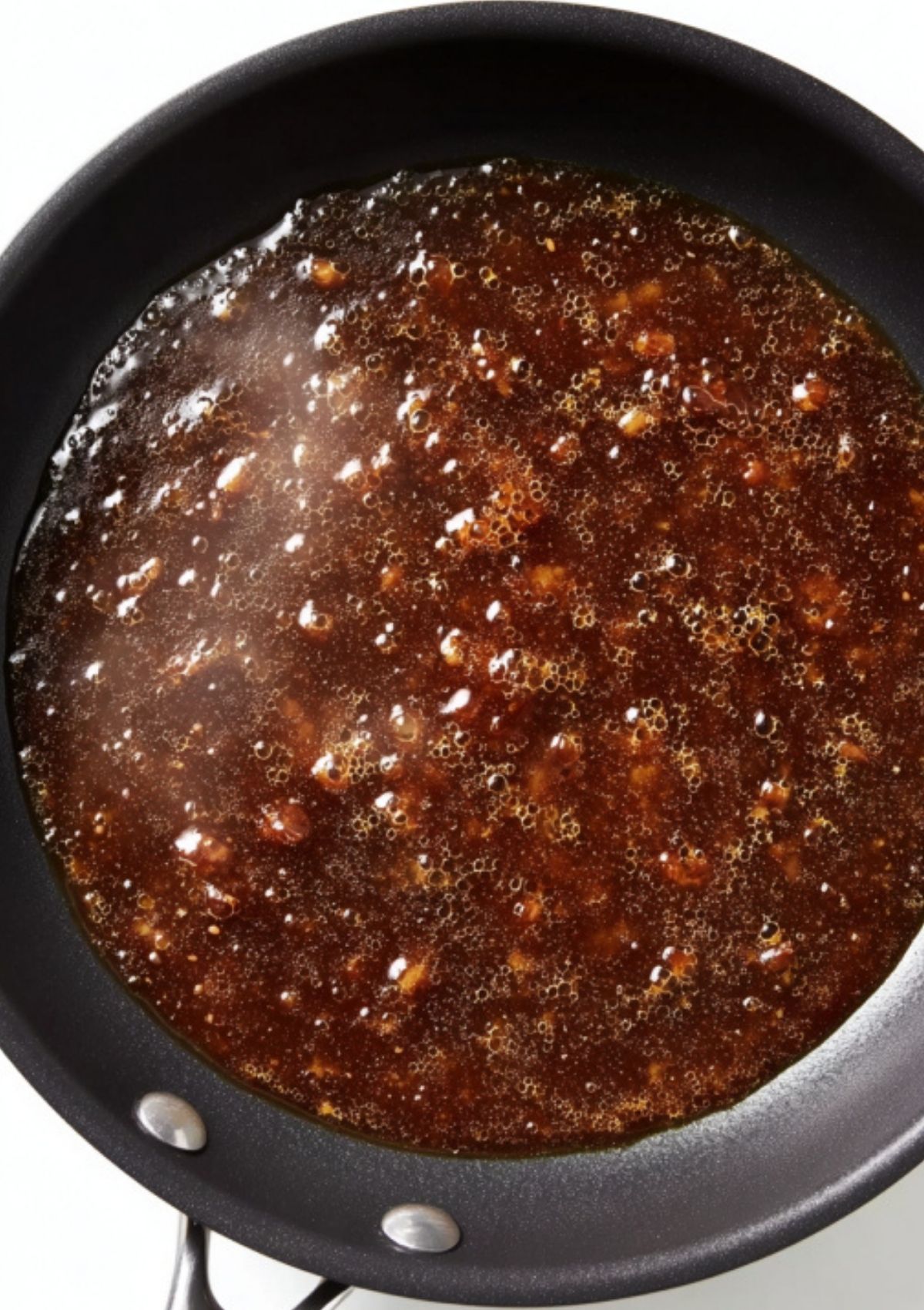 Dark Marsala wine and broth sauce bubbling in a skillet, base for classic scallopini.