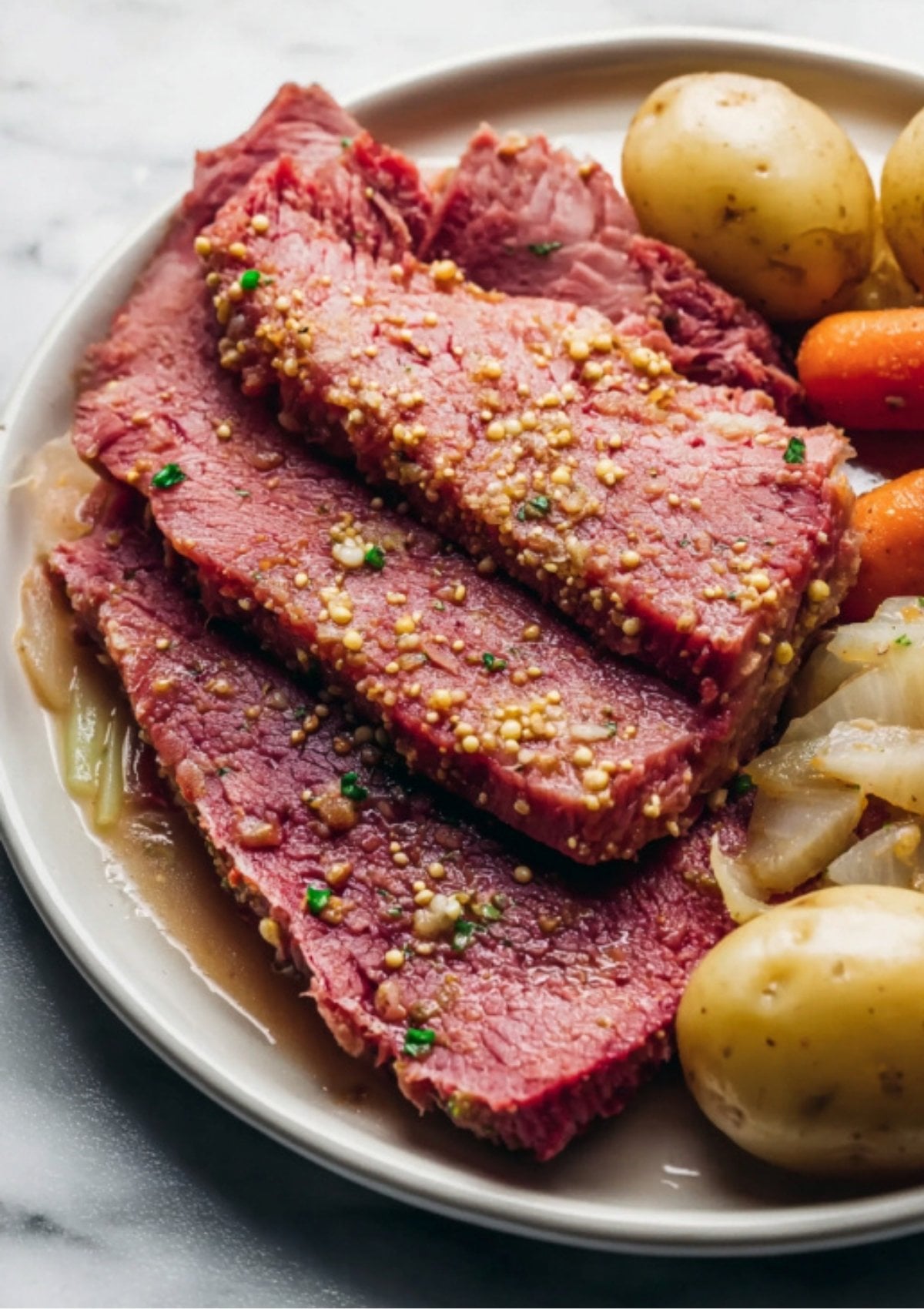 A close-up plate of sliced Instant Pot Corned Beef topped with mustard seeds, served with cabbage and baby potatoes.