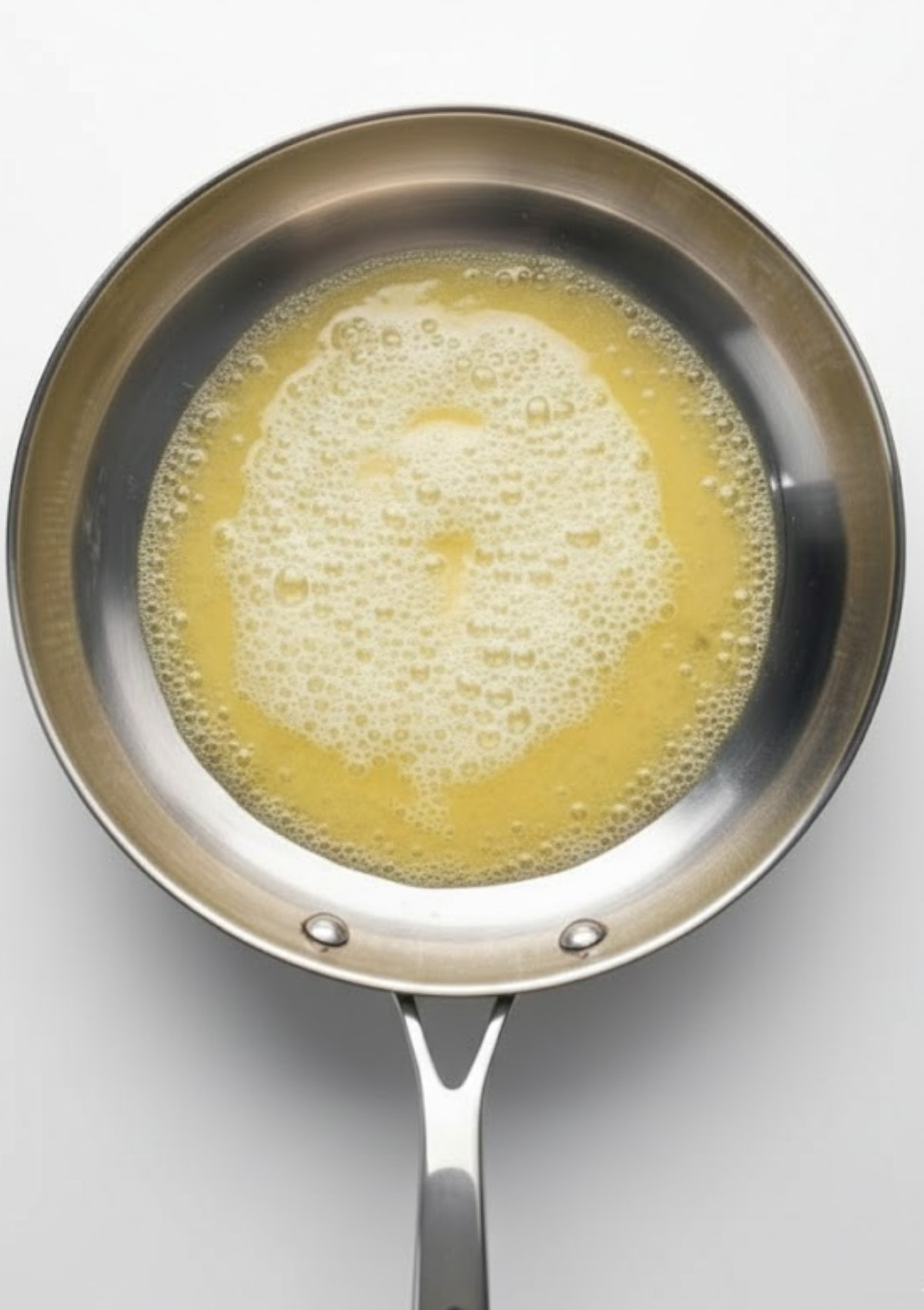 Stainless steel skillet with foamy melted butter, ready for making veal scallopini sauce. Start your Italian veal recipe with this simple base for a tender, flavorful dinner.