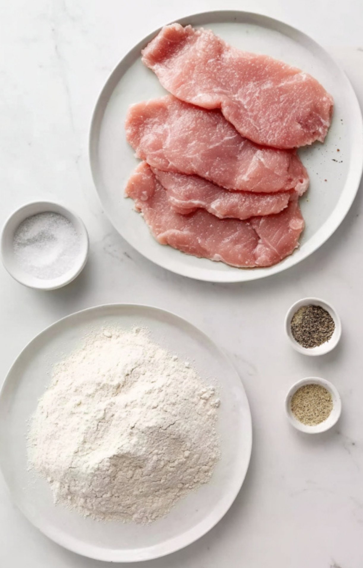 Raw veal cutlets on a plate, with flour, salt, pepper, and dredging ingredients. Simple pantry staples for veal piccata.