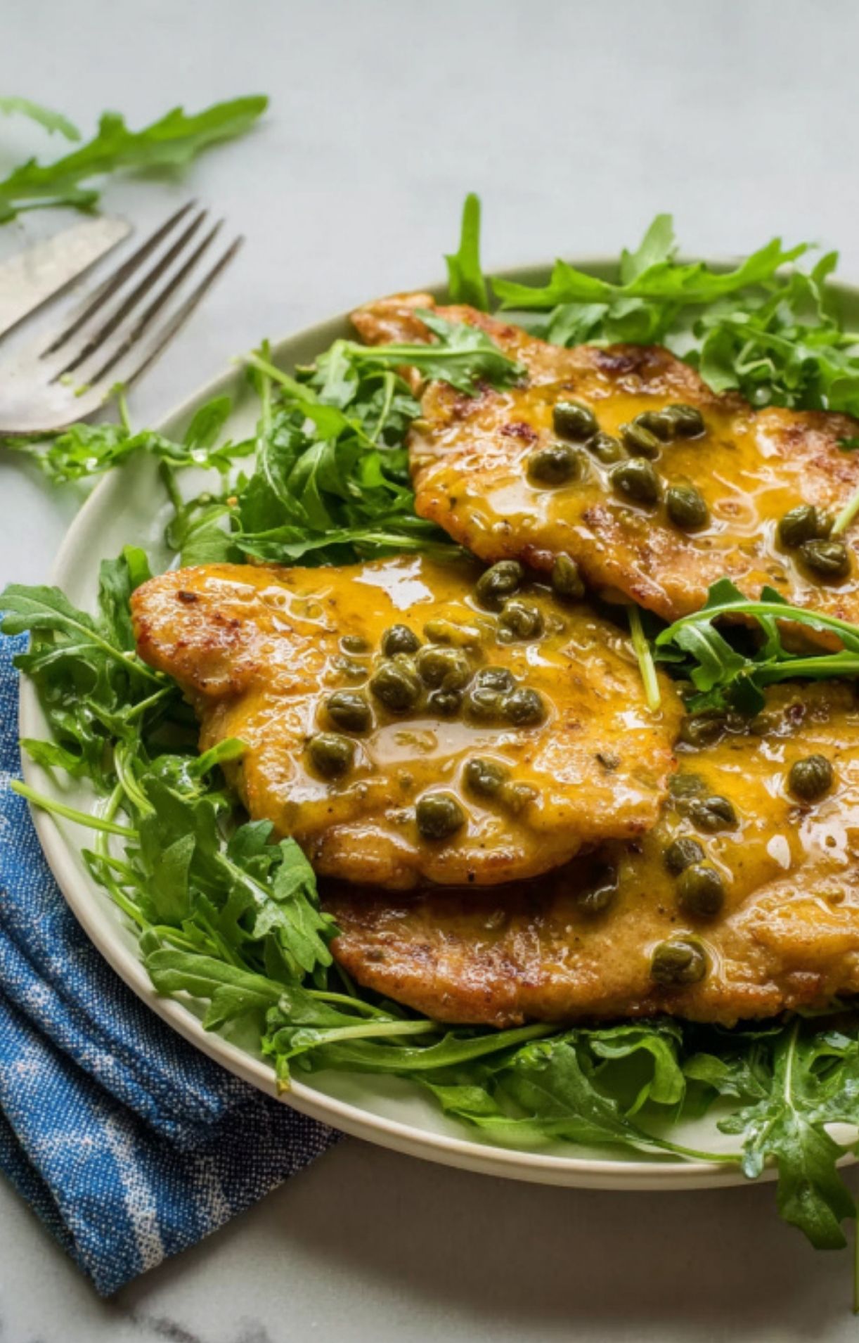 Plated veal scallopini with lemon caper sauce and fresh arugula, an easy Italian dinner for special occasions.
