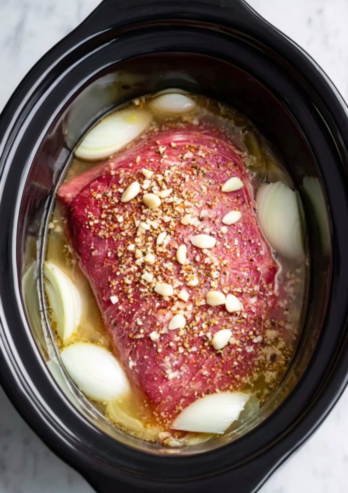 Corned beef brisket resting in broth with onions and seasonings, perfect for an easy holiday recipe or hearty weeknight dinner.
