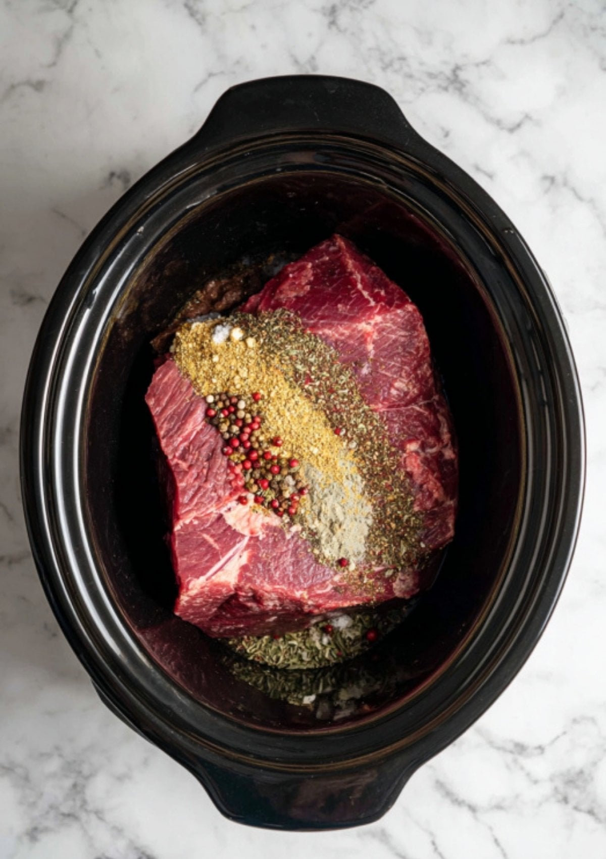 Uncooked brisket in a slow cooker topped with spices and seasonings. Step-by-step guide for making flavorful corned beef at home, perfect for easy weeknight meals or festive occasions.