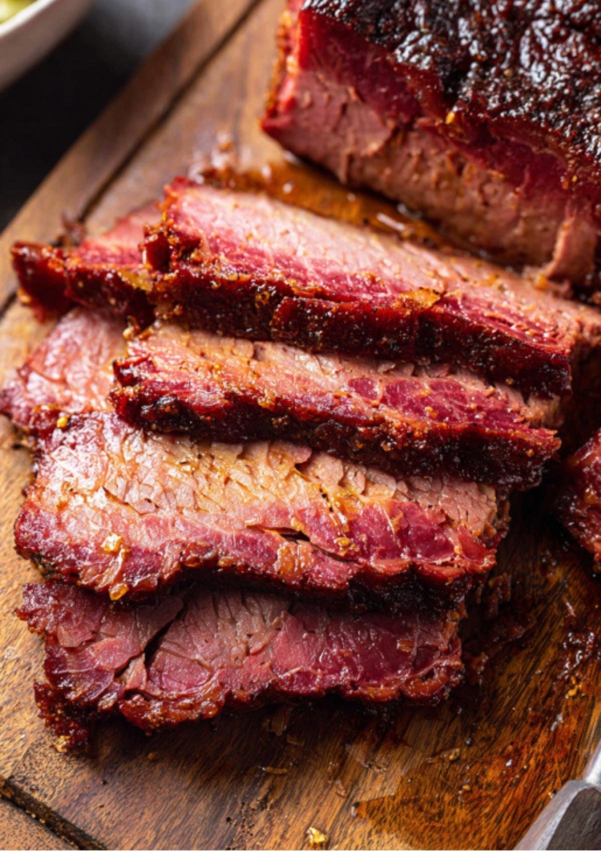 Sliced oven baked corned beef on a cutting board showing crispy edges and juicy texture. This simple baked brisket is perfect for meal prep, holiday feasts, and family meals.