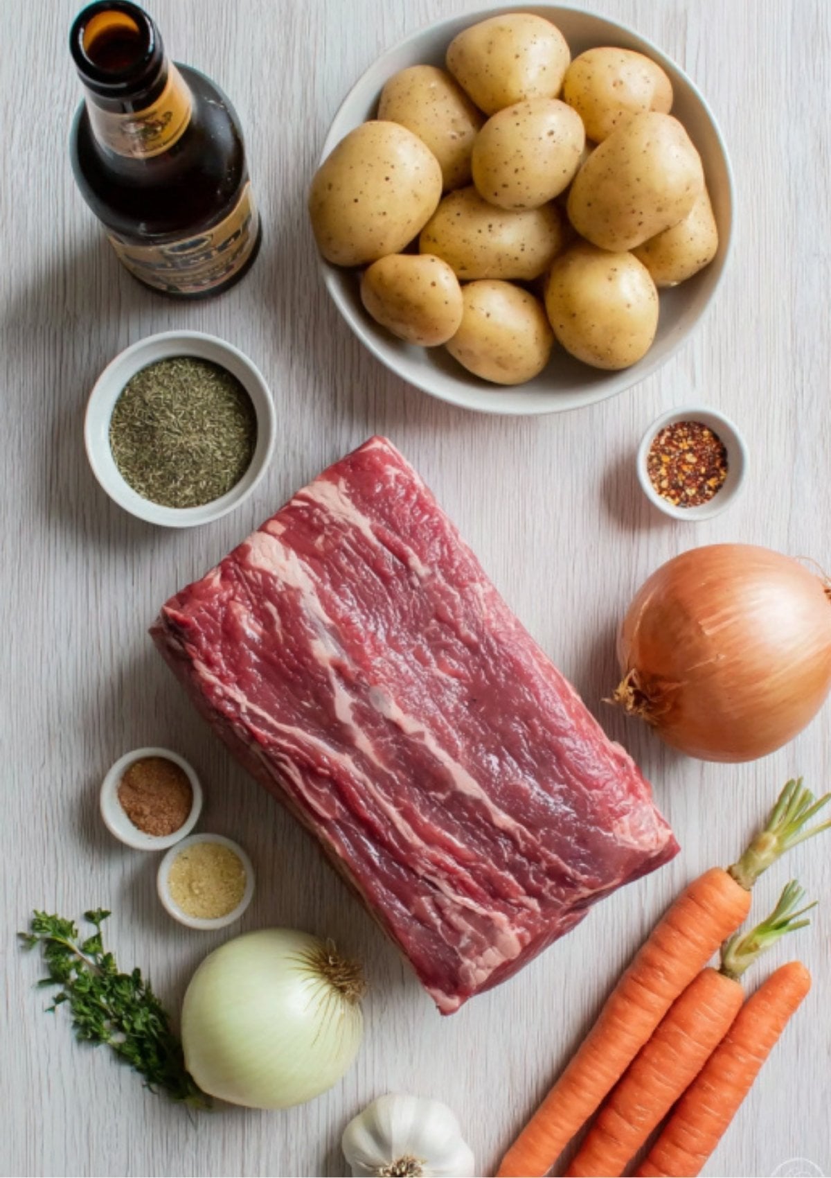 Overhead view of raw beef brisket, potatoes, carrots, onions, garlic, stout beer, and various spices ready for making Instant Pot Corned Beef.
