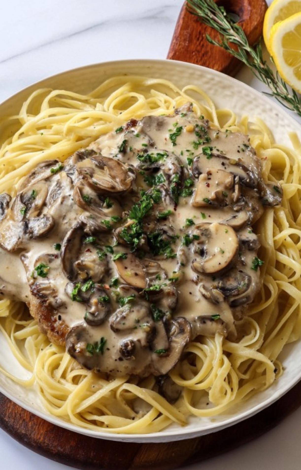 Veal scallopini with creamy mushroom sauce served over a bed of pasta, garnished with fresh parsley for an Italian family meal.