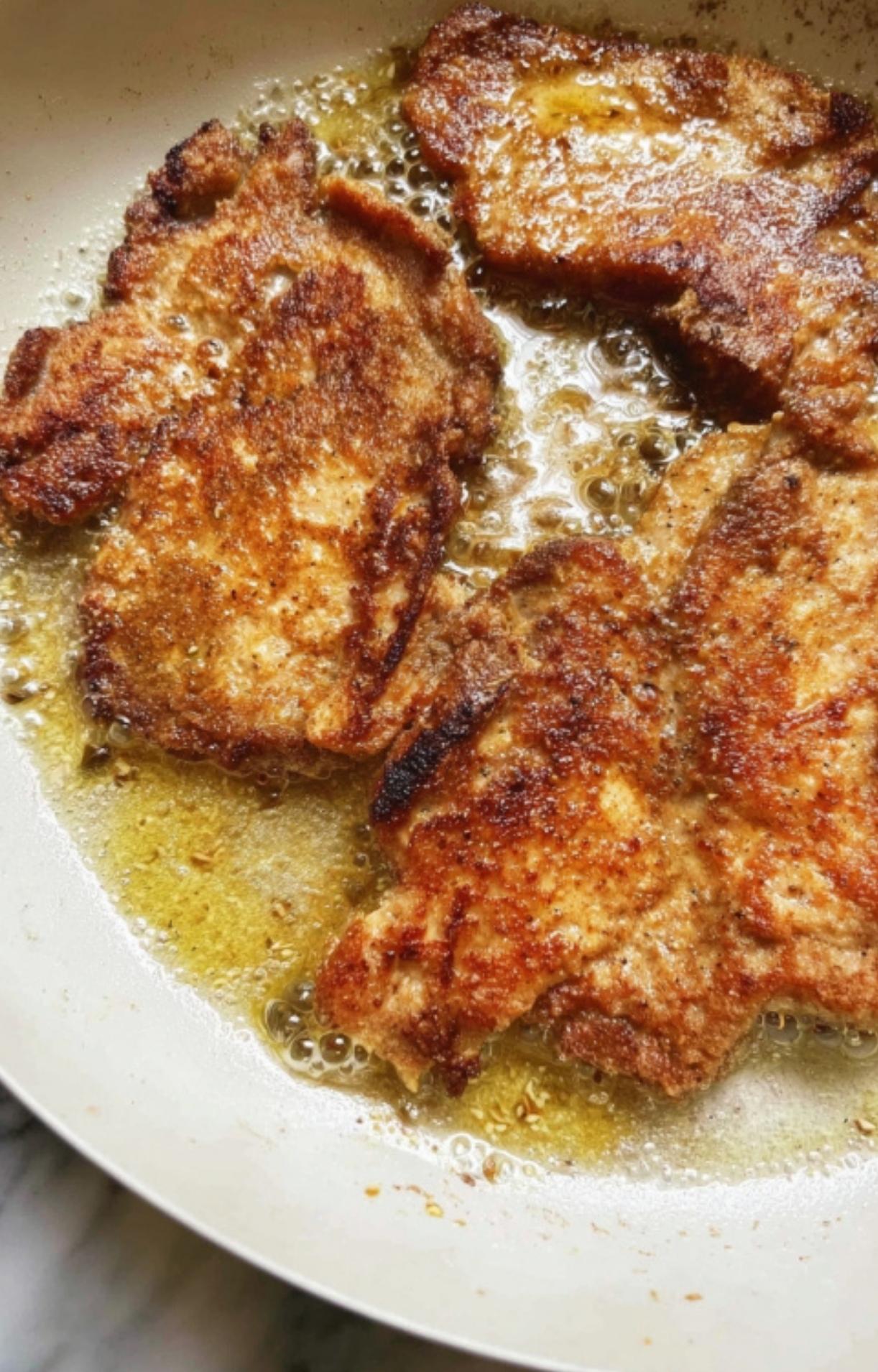 Thin veal cutlets browning in a hot skillet with a golden crust. Ideal for Italian weeknight dinners and elegant spring recipes.
