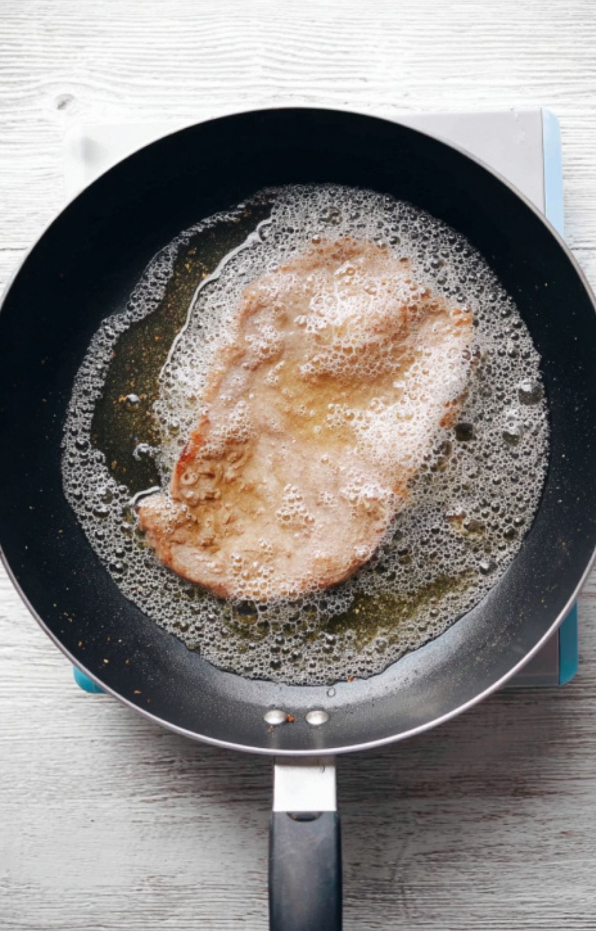 Veal cutlet frying in butter in a skillet, bubbling and golden, showing the key step for juicy and flavorful scallopini.