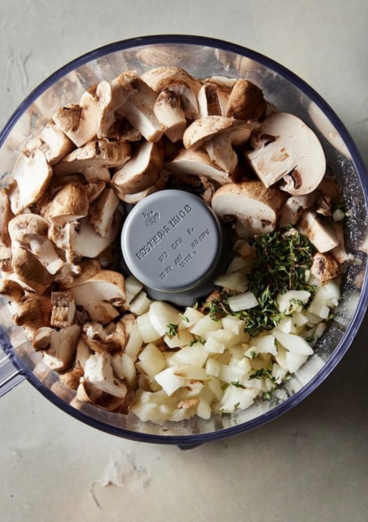 Mushrooms, onions, and fresh thyme in a food processor, creating a flavorful filling for classic beef Wellington puff pastry, perfect for a gourmet main dish.