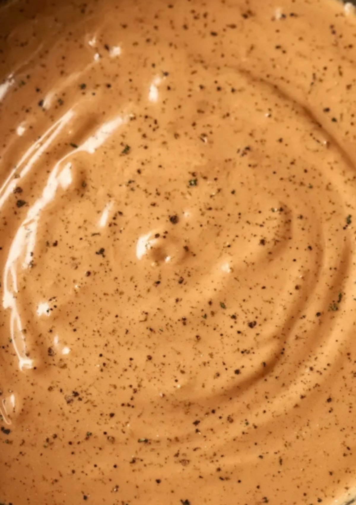 Smooth and glossy black peppercorn cream sauce closeup, showing thick, rich texture ideal for steak, roast beef, or Beef Wellington.