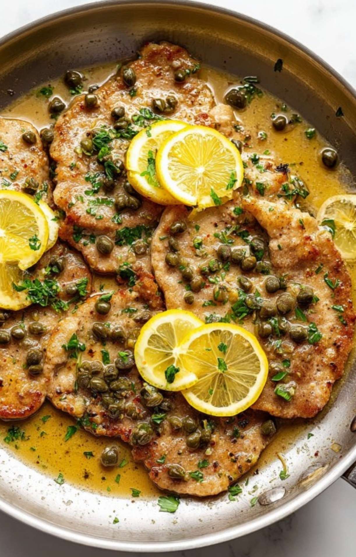 Veal cutlets cooking in a skillet until golden brown. Quick and easy Italian cooking method.