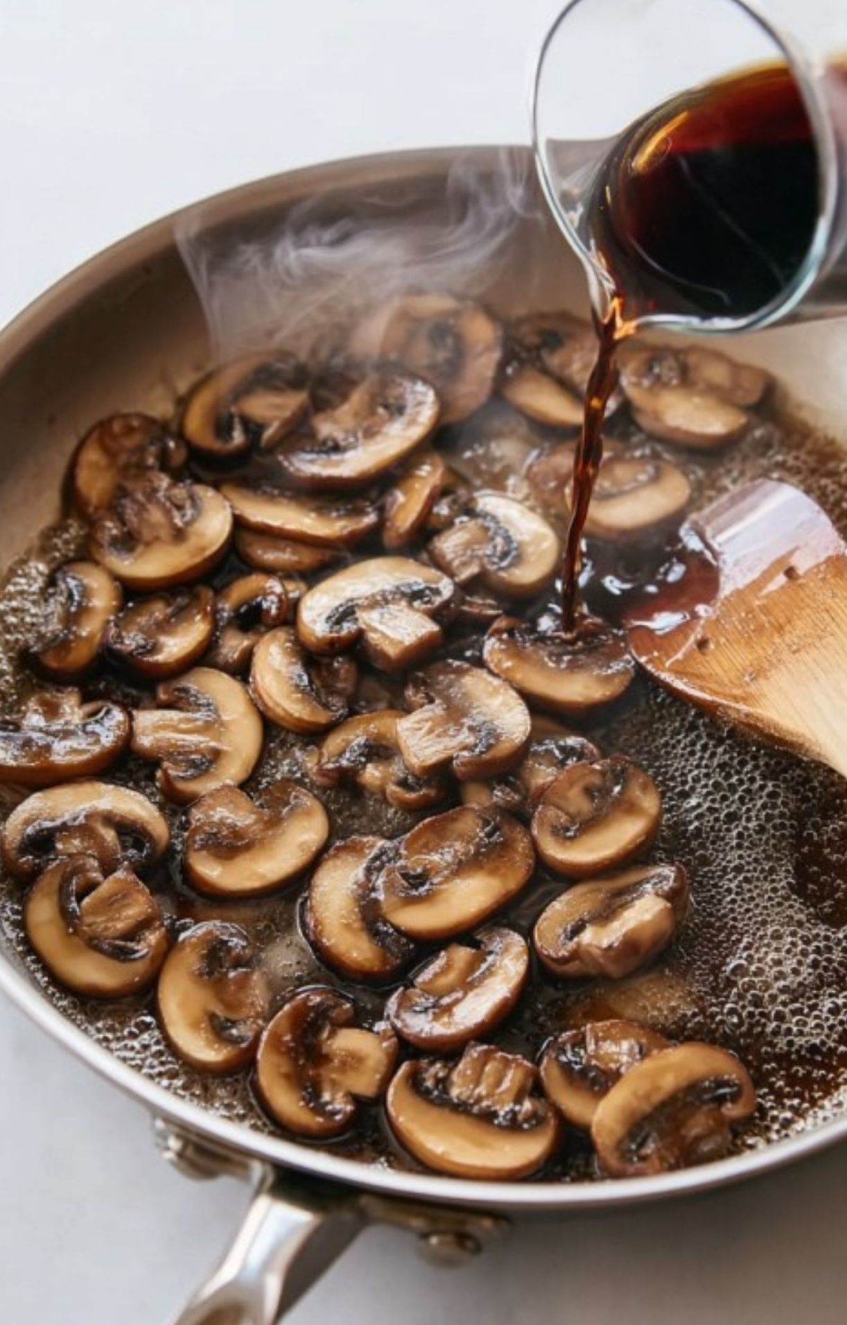 Adding Marsala wine to sliced mushrooms in a hot skillet, creating a rich Italian sauce for veal