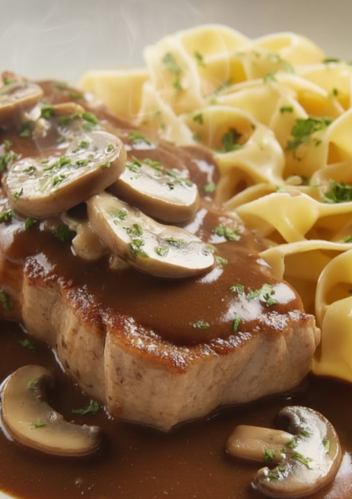 Plate of veal scallopini smothered in mushroom marsala sauce, served with egg noodles and sprinkled with parsley.