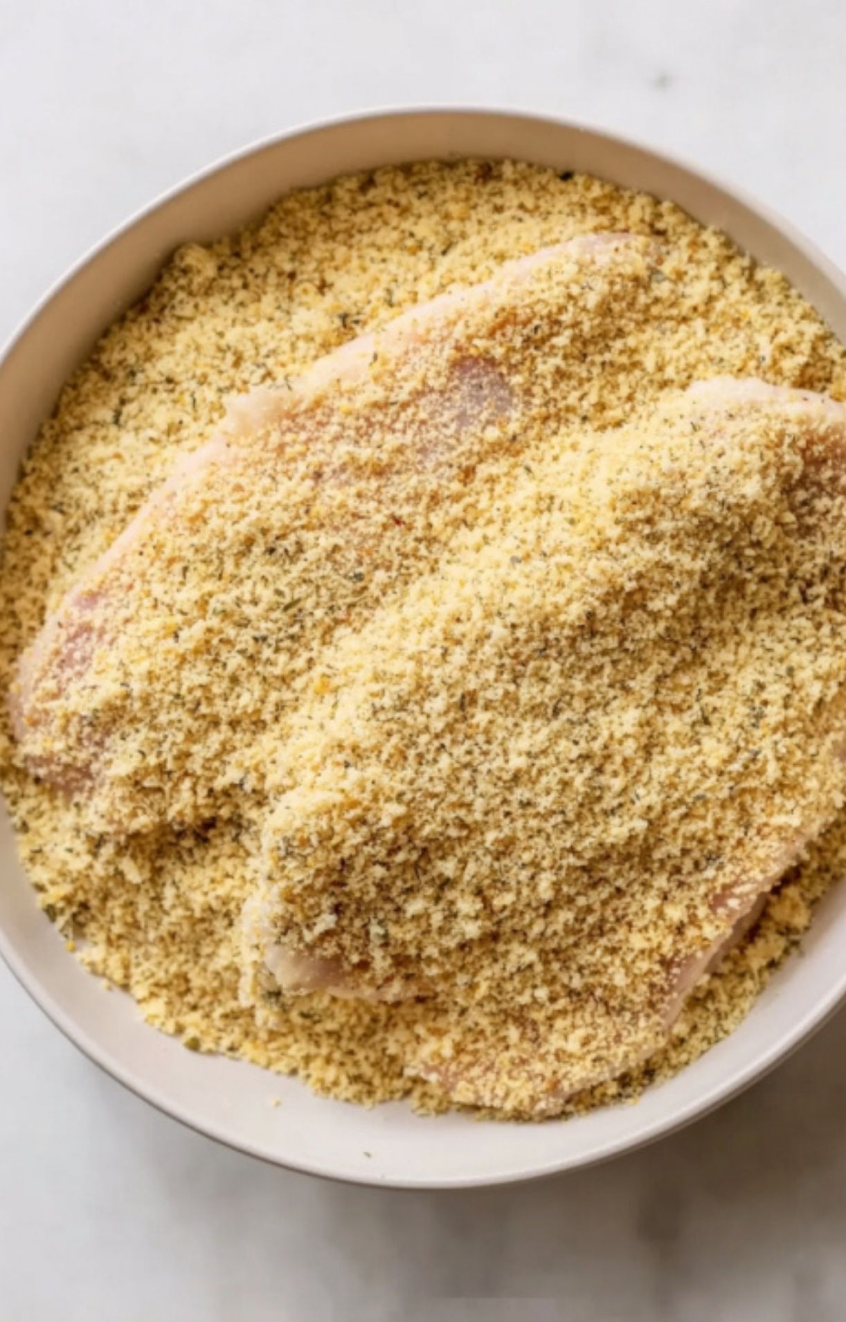 Veal cutlets fully coated in seasoned breadcrumbs, ready for frying to make classic Italian Parmesan