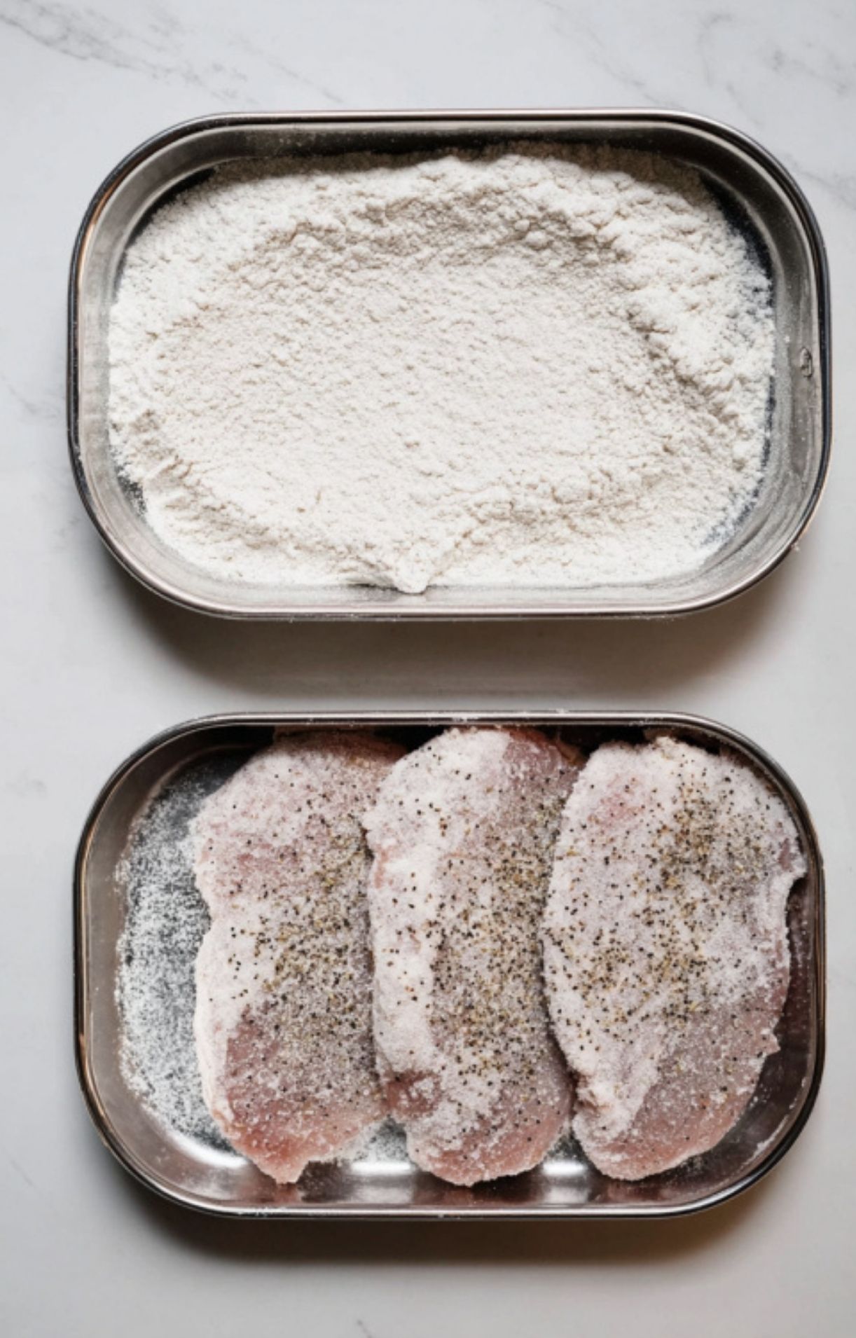 Seasoned veal cutlets fully coated in flour, prepared for searing in a creamy mushroom sauce recipe.