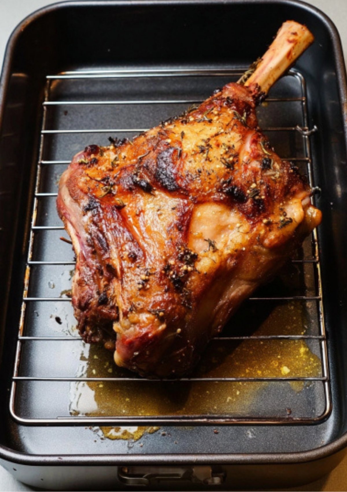 Golden roasted leg of lamb resting in a roasting pan