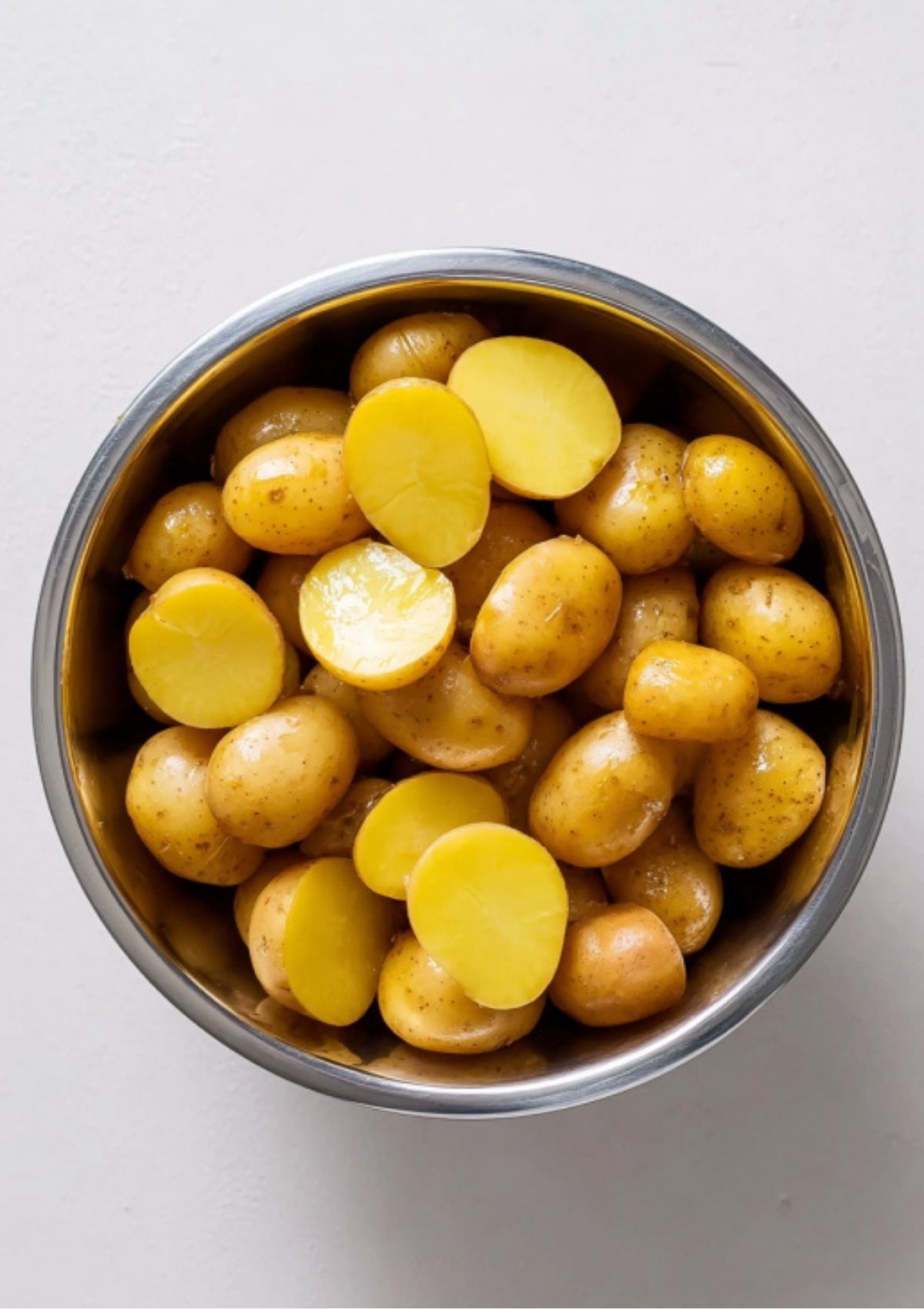 Bowl of baby potatoes, some halved and some whole, ready to be roasted