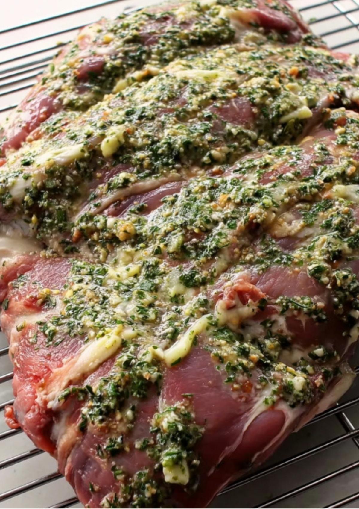 Hand slicing into the roasted lamb, showing juicy pink slices on a cutting board