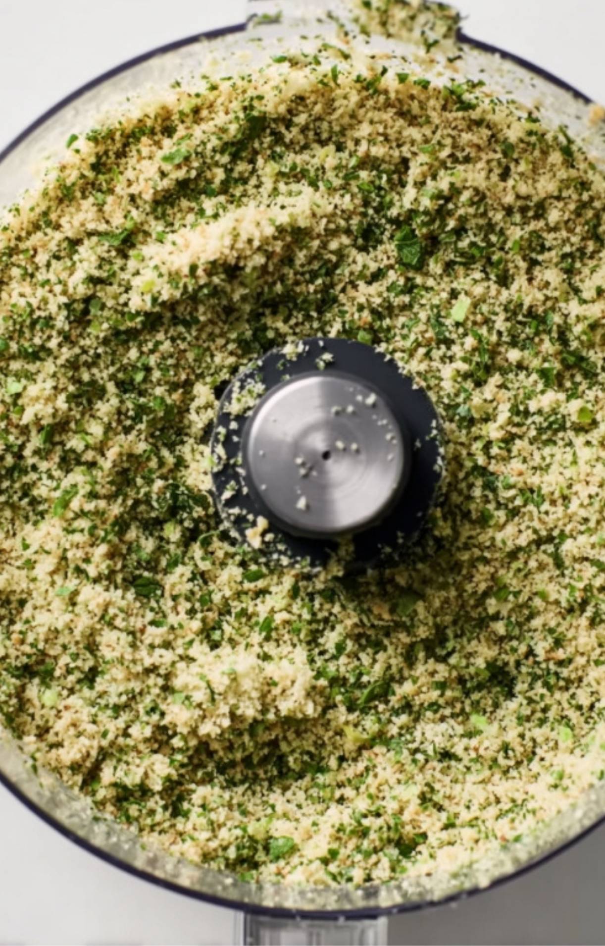 Fresh green herb and breadcrumb mixture in food processor, perfect for coating rack of lamb